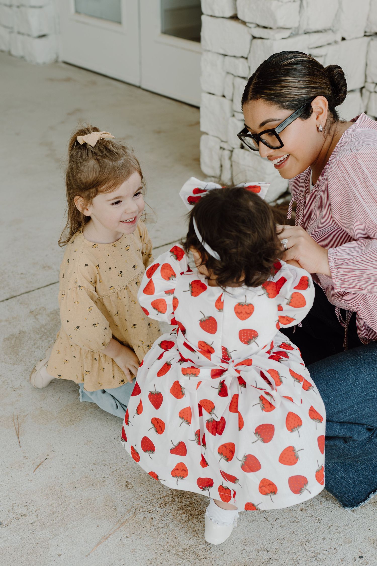 Sweet moment captured on white stone floor with heart-patterned dress and casual attire.