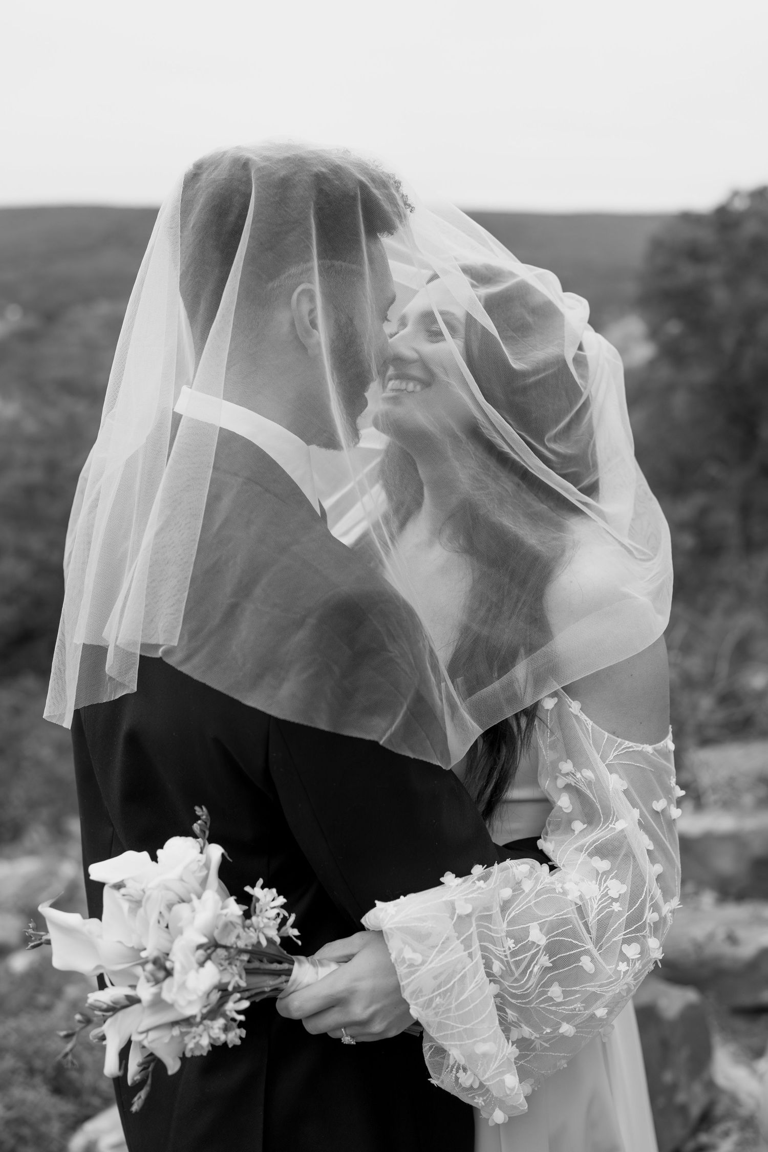 Close-up of wedding veil flowing in the wind with delicate floral details.