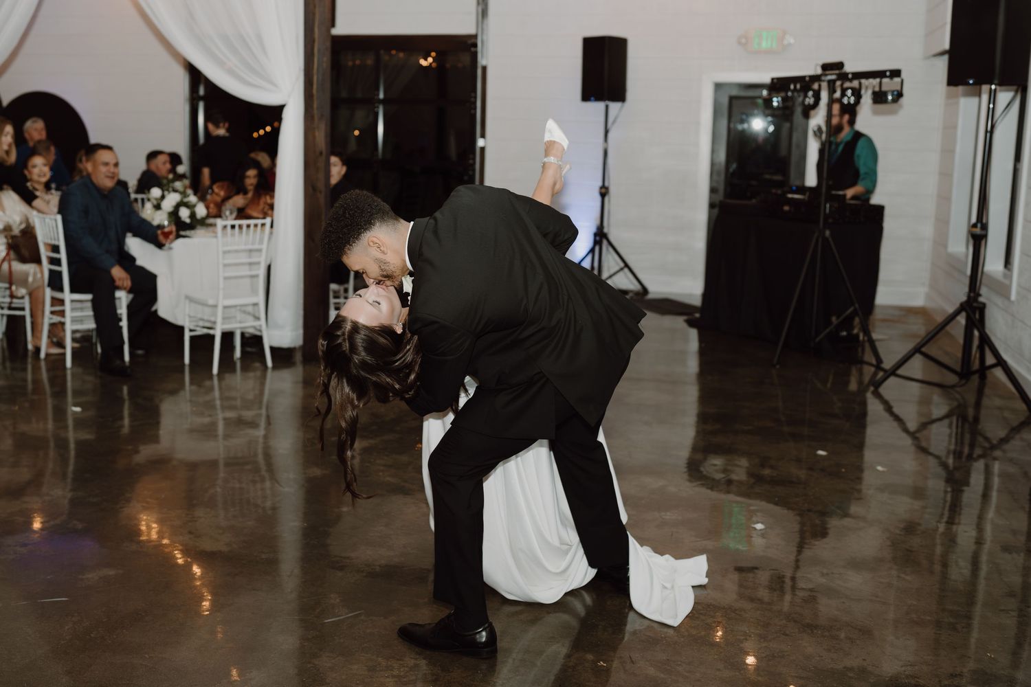 Wedding guests watch as a couple performs their first dance in an industrial-style reception venue.