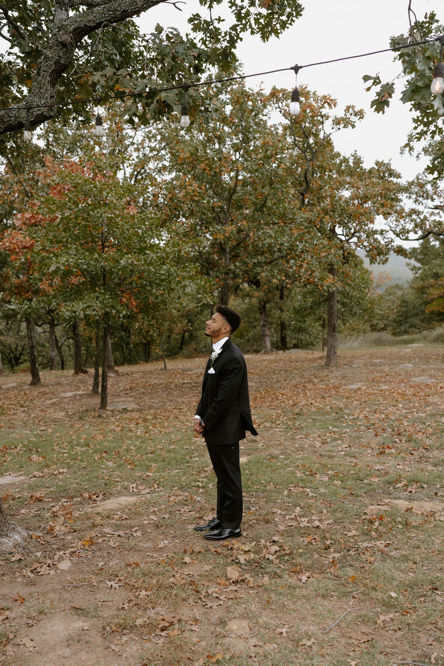 A couple shares a romantic first look moment in an autumn woodland setting.