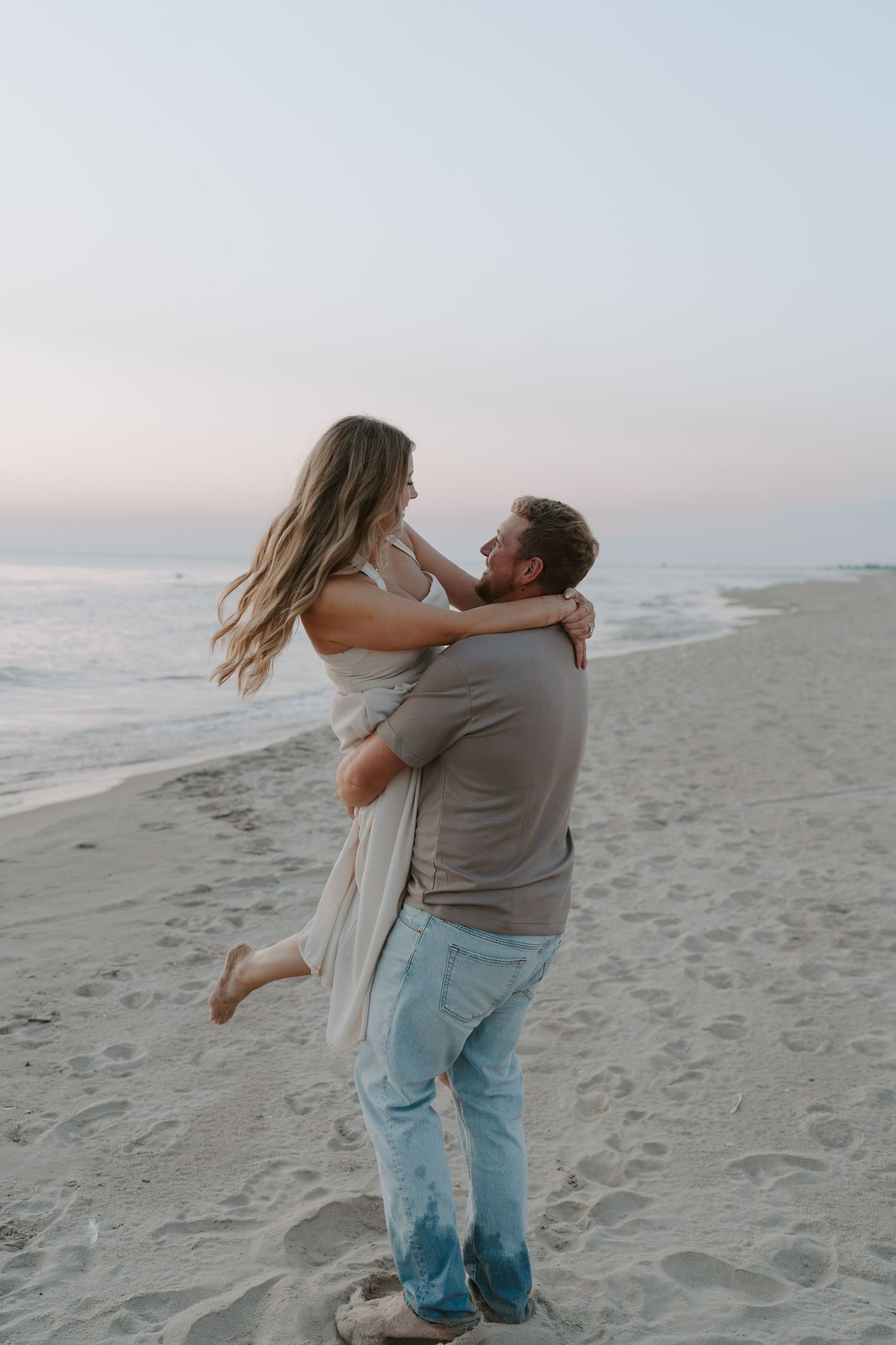 Romantic couple embracing and dancing together on a sandy beach at sunset.
