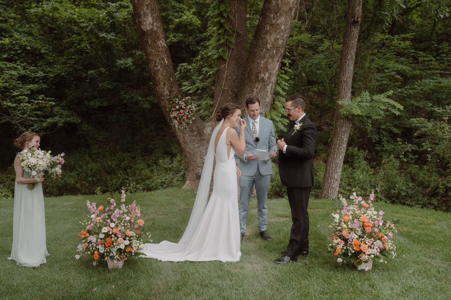 Outdoor wedding ceremony with floral arrangements and natural forest backdrop.