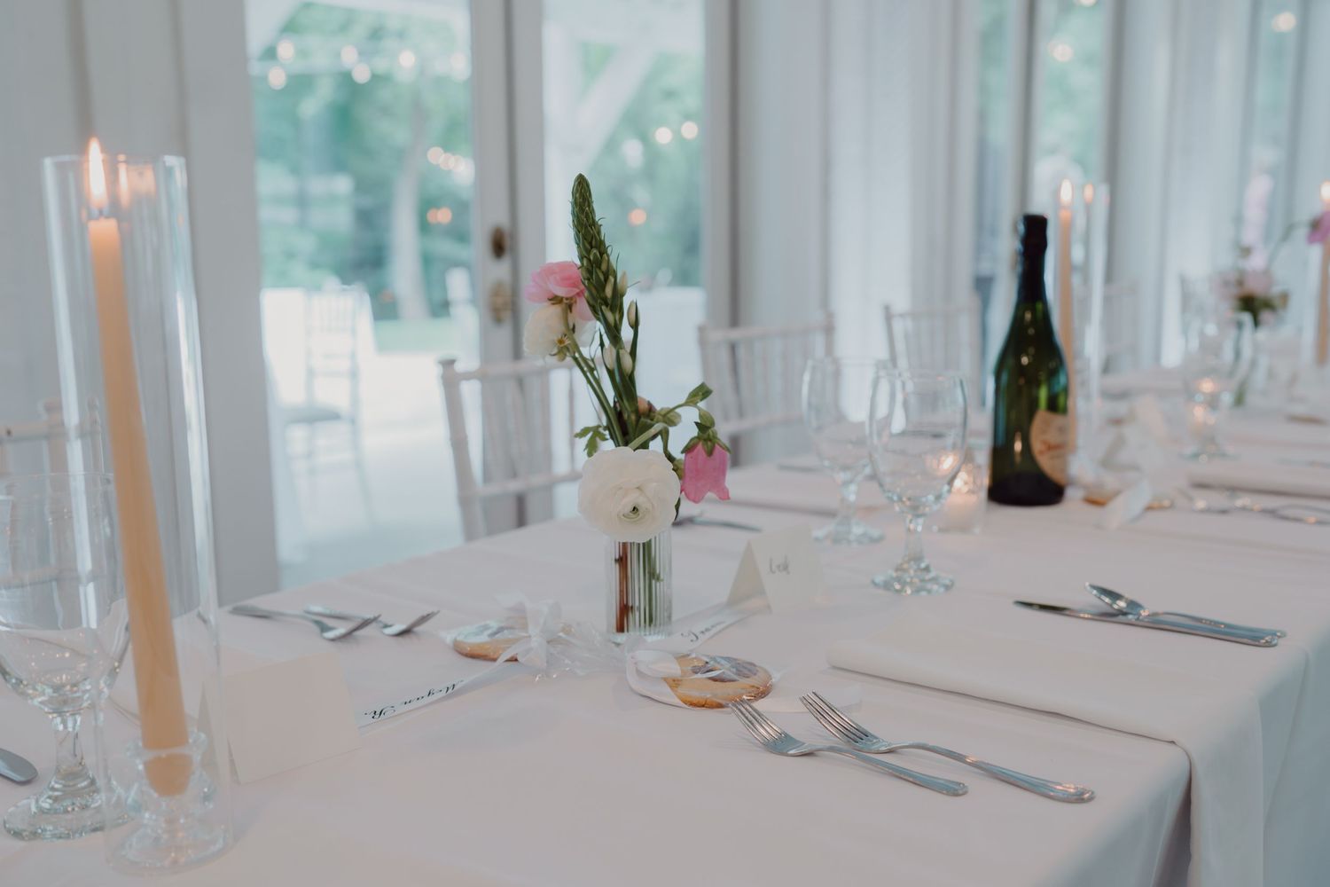 Light-filled dining room with white tables set for formal celebration.