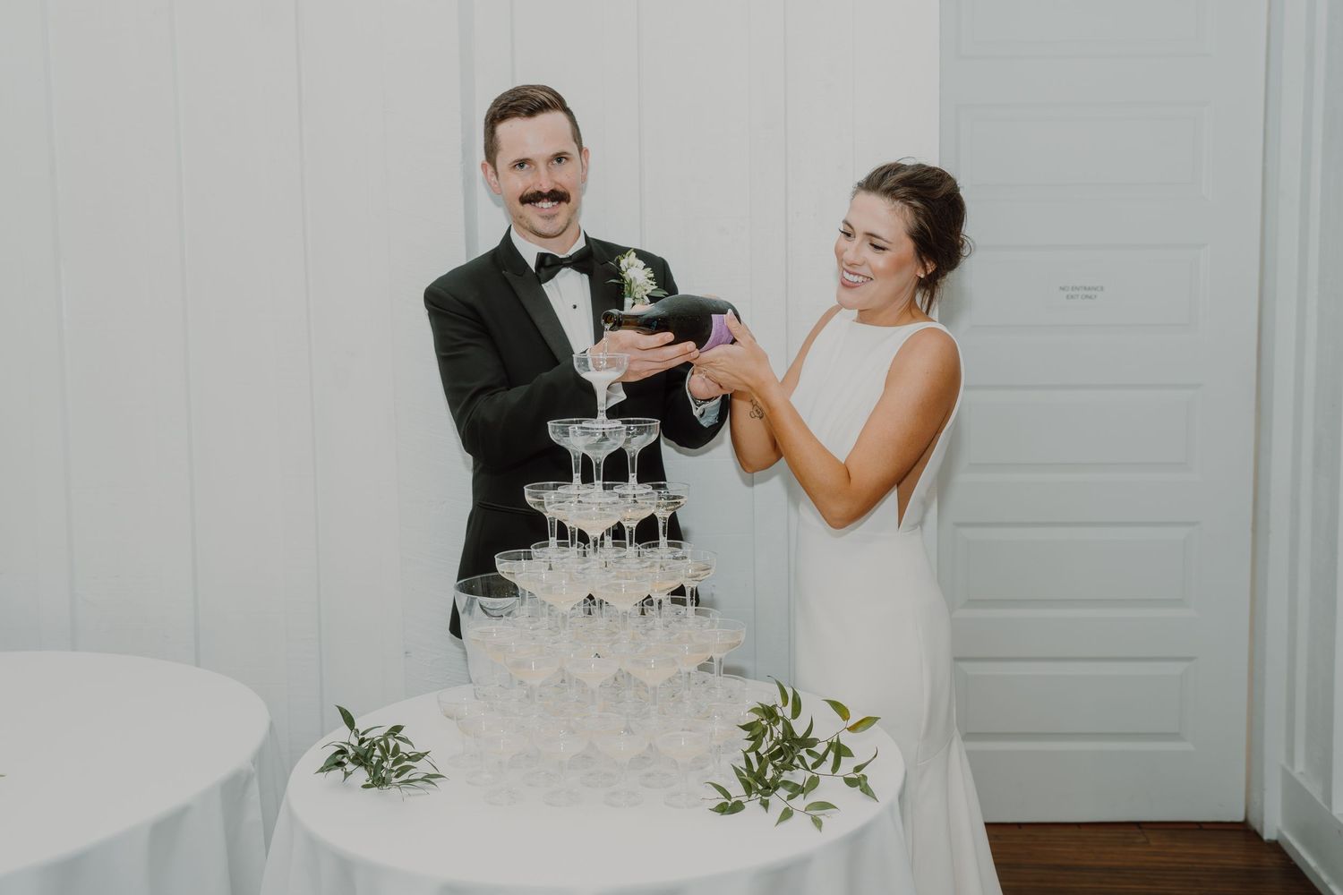 Champagne being poured into a tower of stacked glasses at an elegant wedding reception.