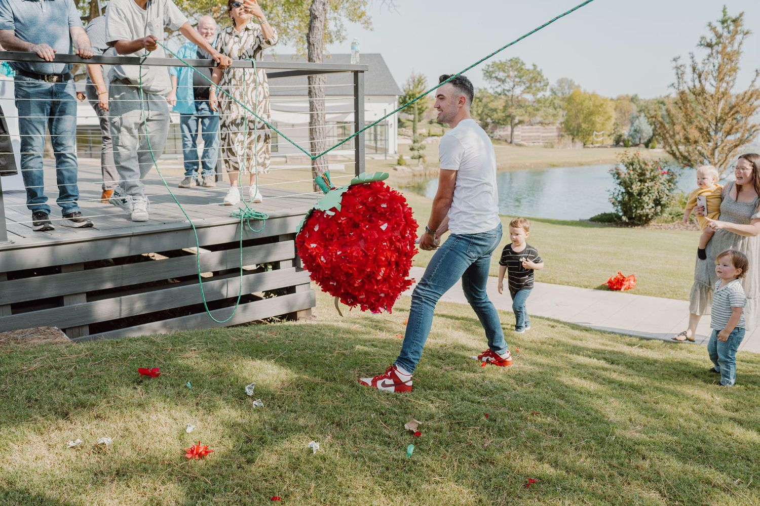 Multiple people collecting bright red decorative pieces spread across a green lawn.