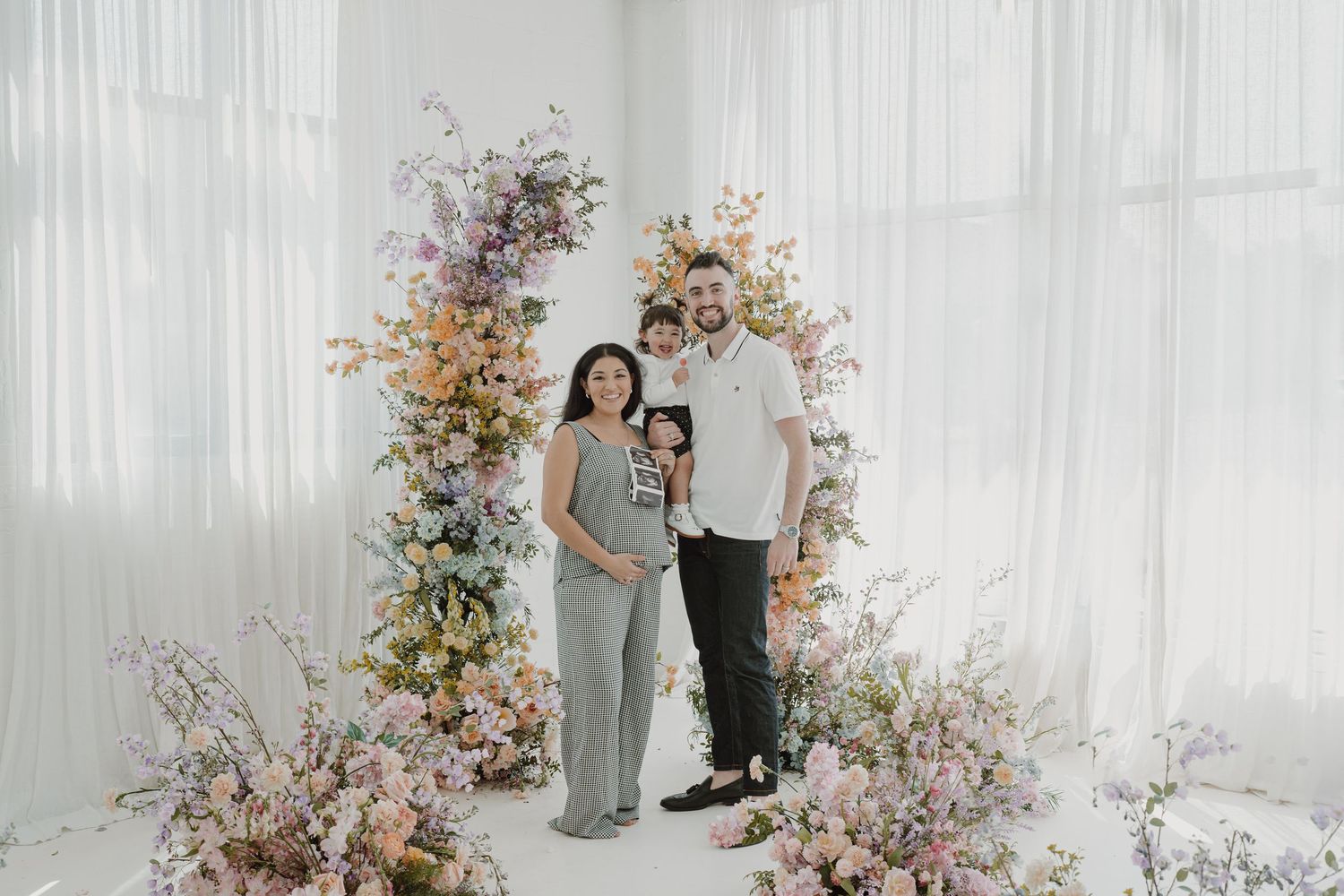 Professional photography session with floral installations in a bright white studio space.