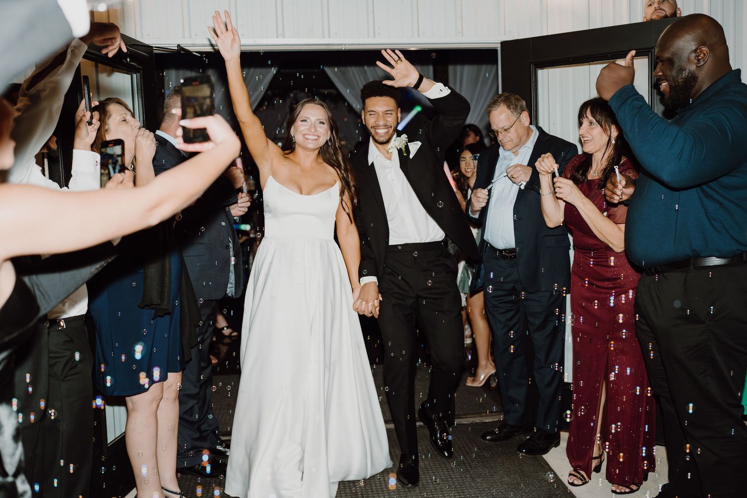 Guests dancing and celebrating at a wedding reception under white draped decor.