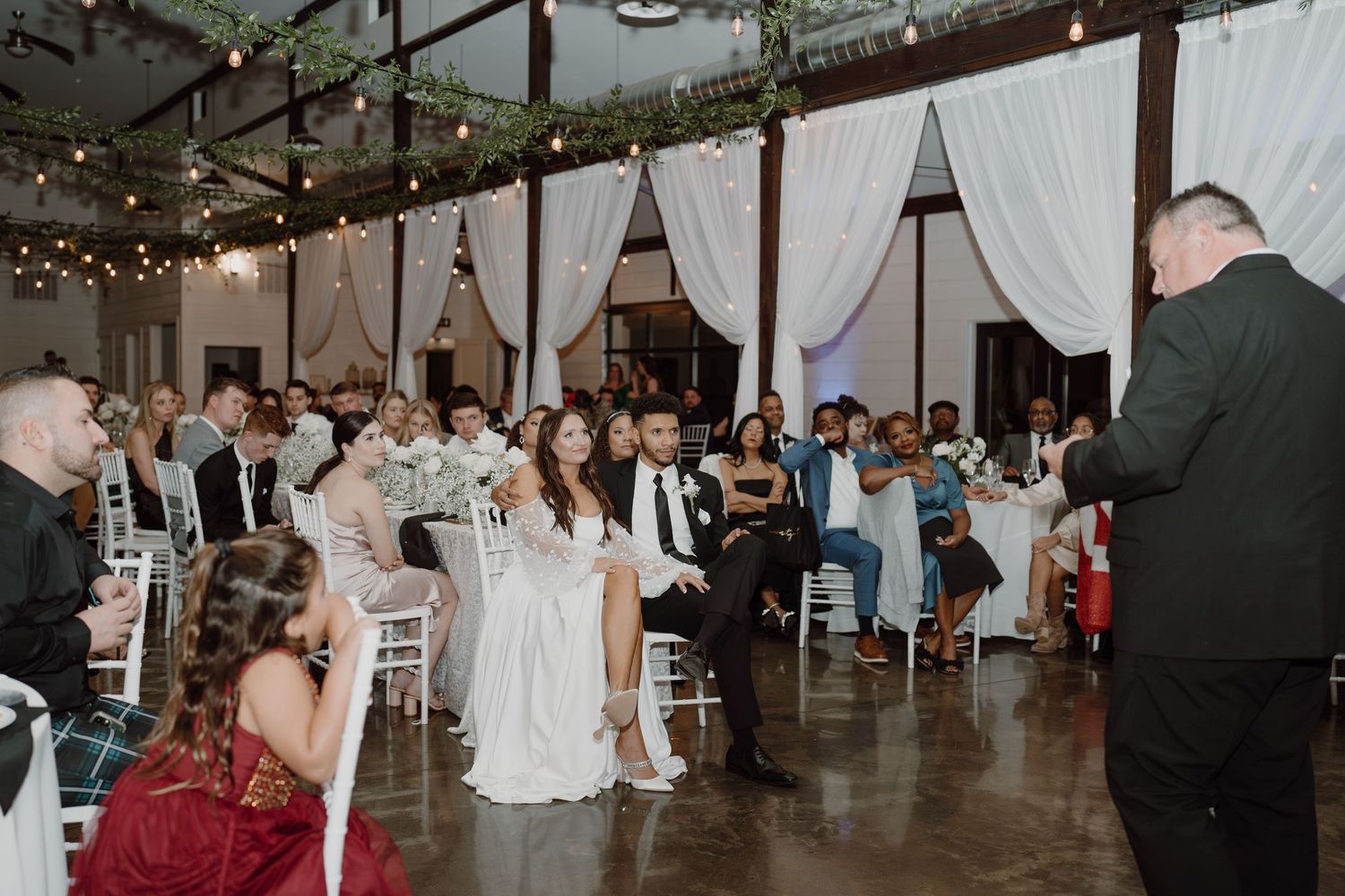 Modern wedding venue with elegant white decor and twinkling lights during evening reception.