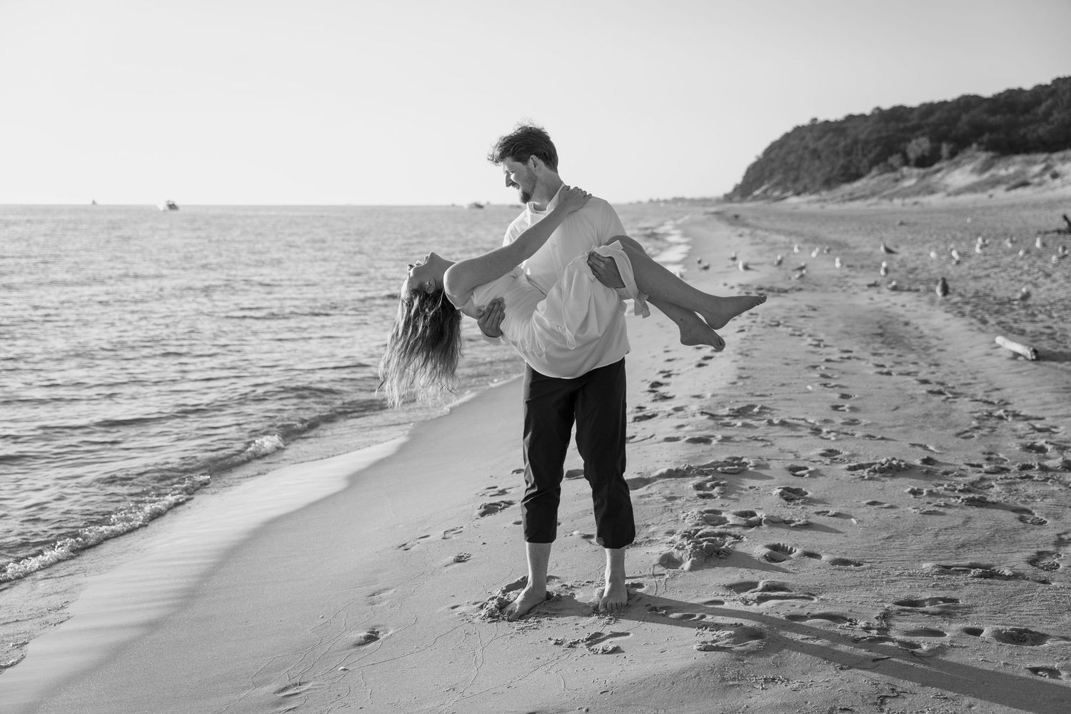 Black and white beach portrait of couple playing in the surf.