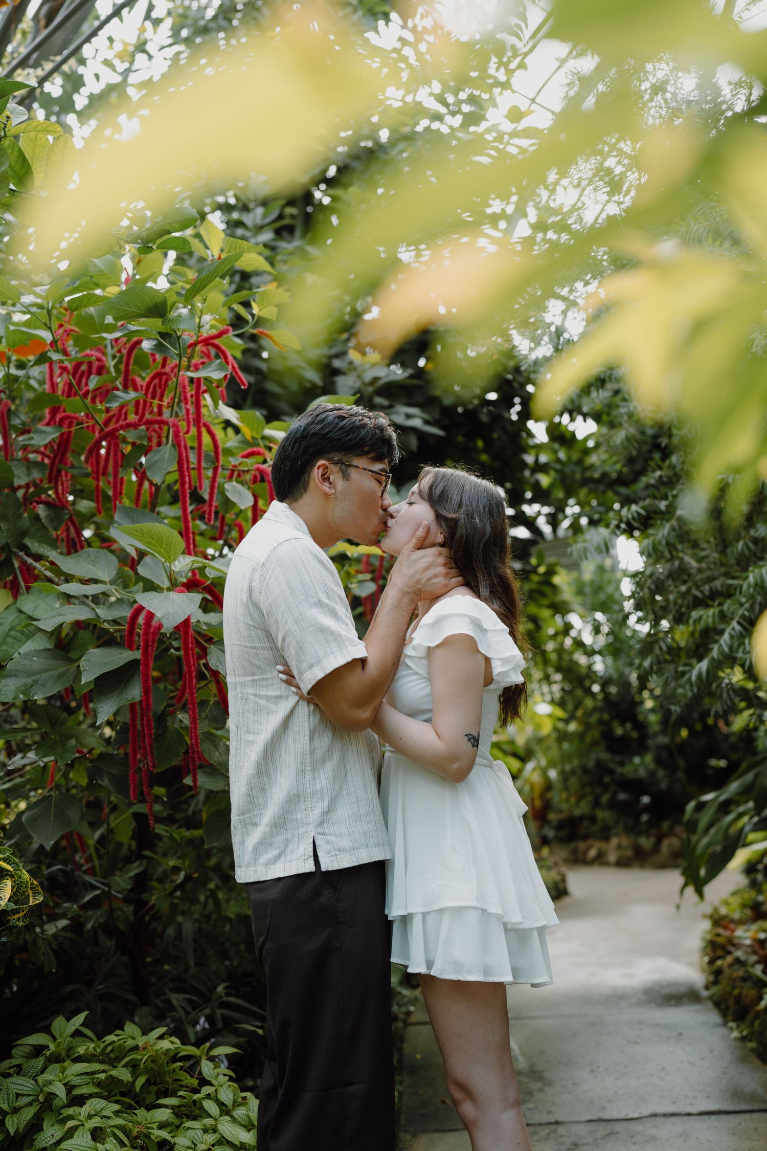 A tender embrace captured in a garden setting with soft natural lighting and verdant foliage.