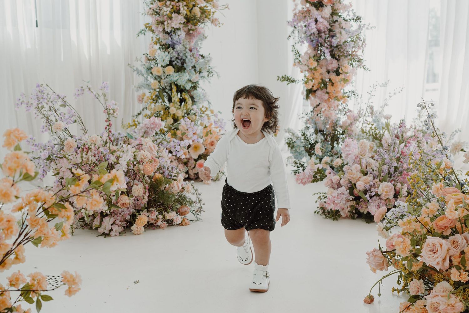 Dynamic photo sequence showing playful moments against a backdrop of pastel floral decorations.