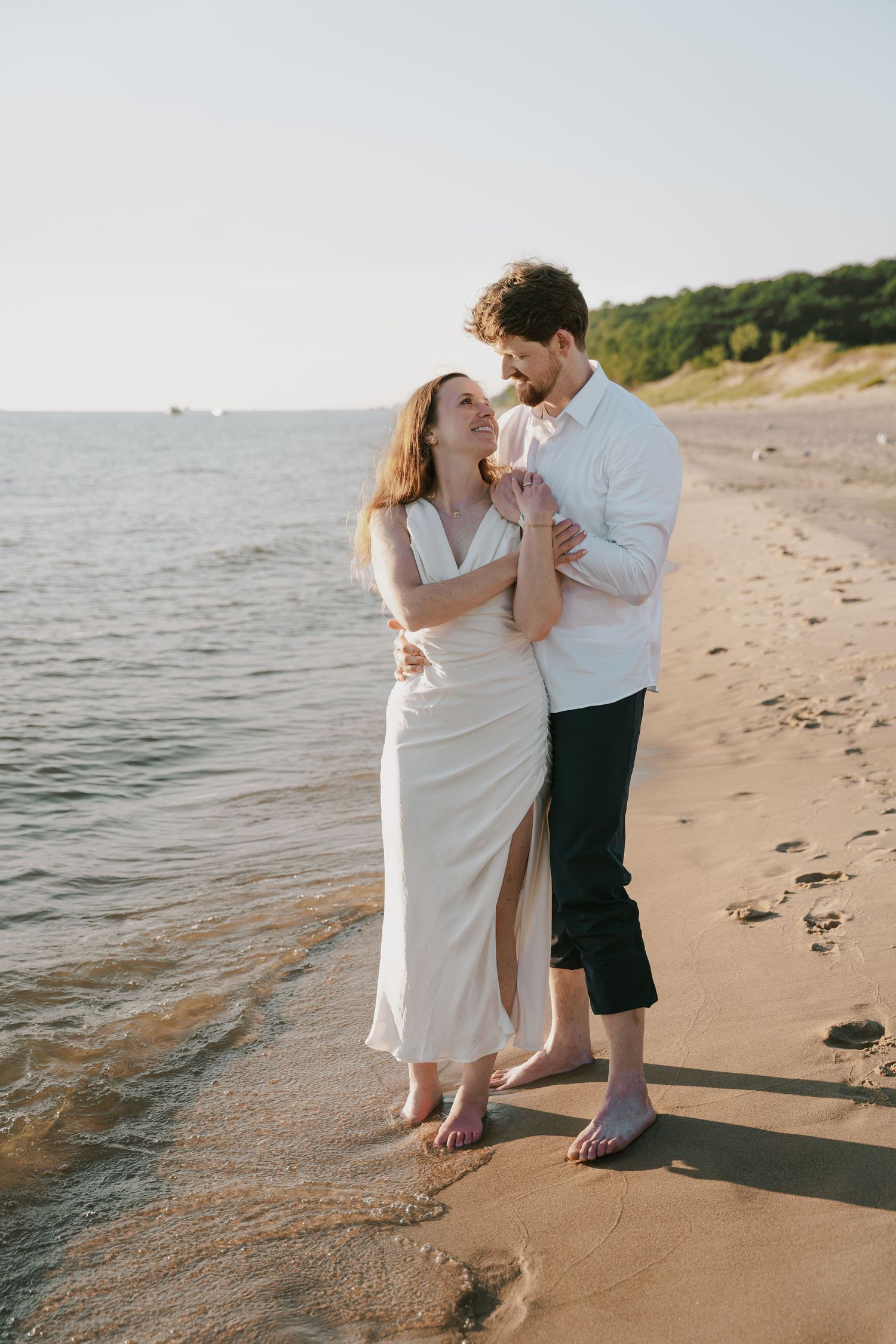 A couple dances together on the beach as waves roll onto the shore.