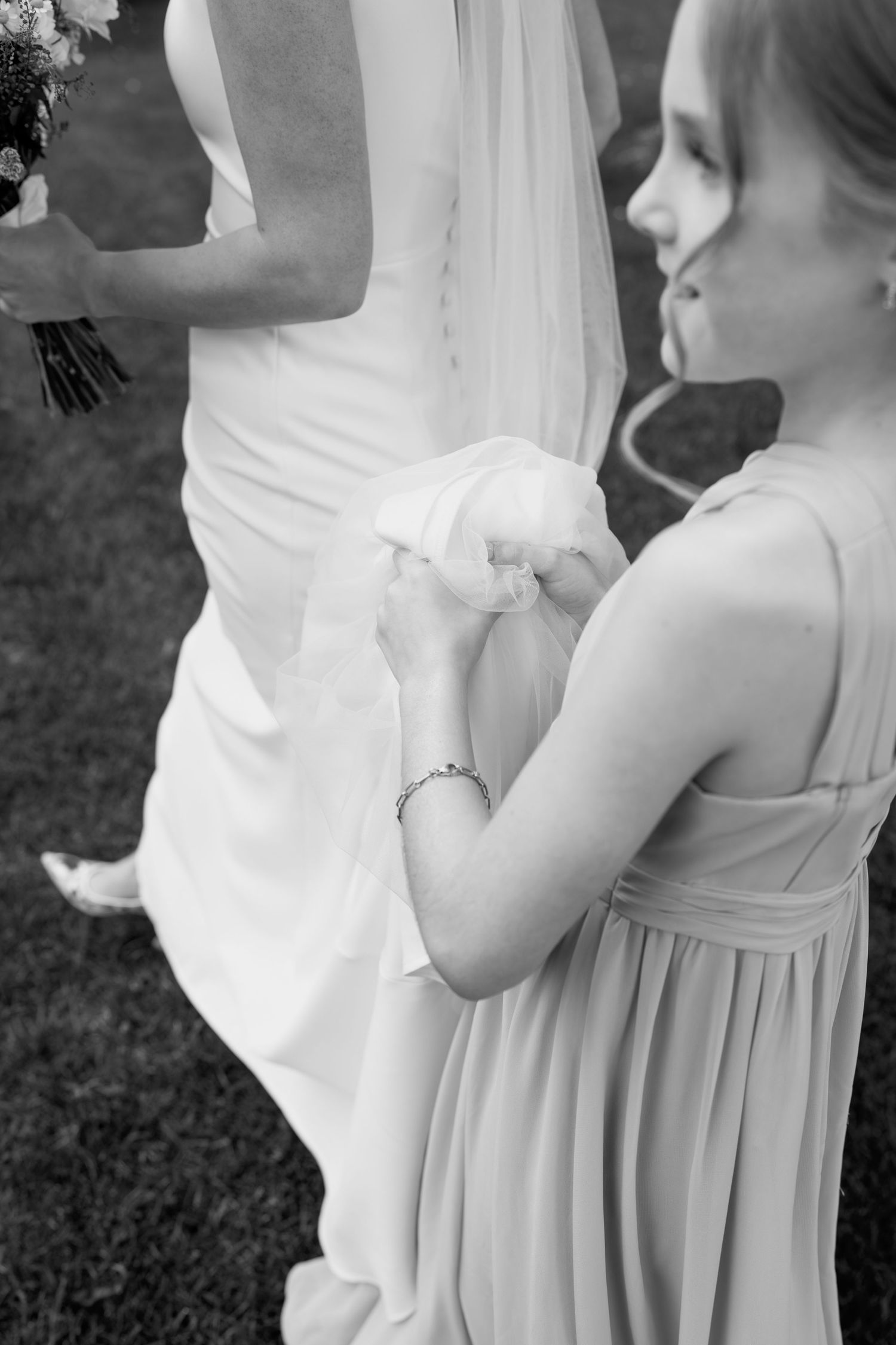 Black and white close-up of two people in formal attire sitting together outdoors.