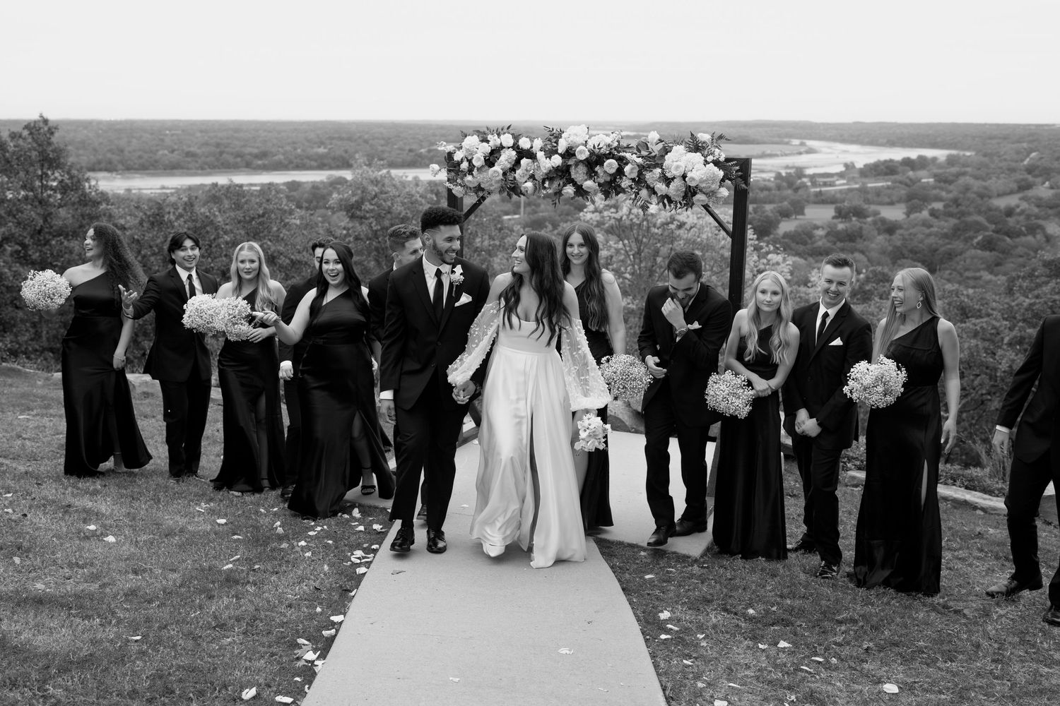 Wedding ceremony panorama showing guests lined up along a decorated pathway with scenic backdrop.