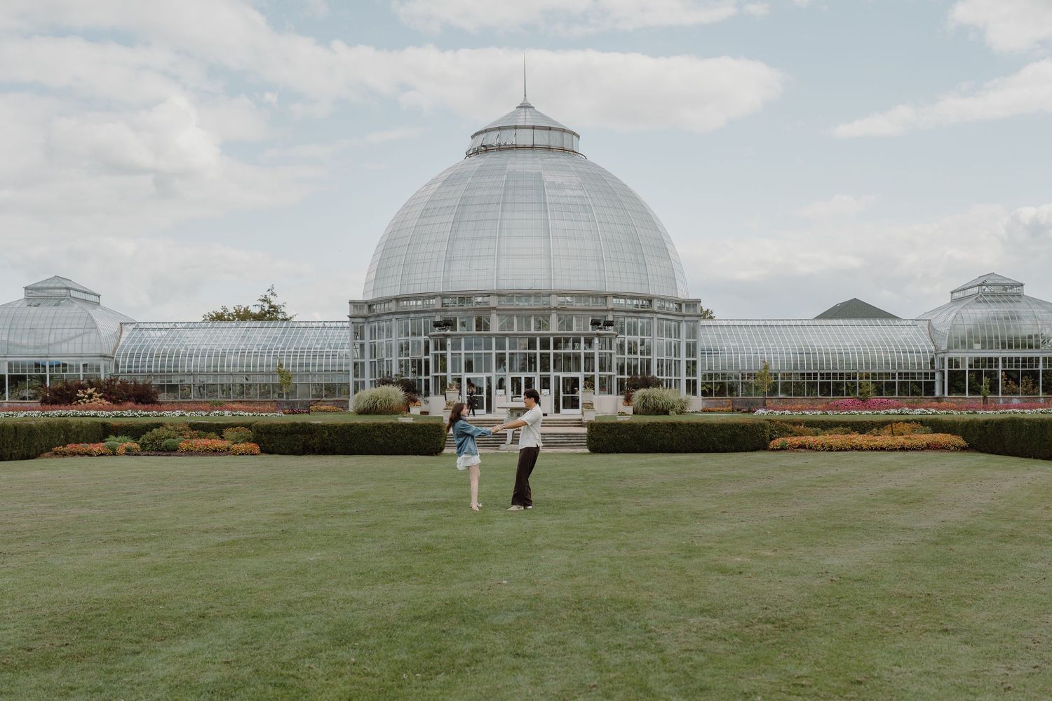 Wide view of a glass conservatory building with visitors enjoying the landscaped grounds.
