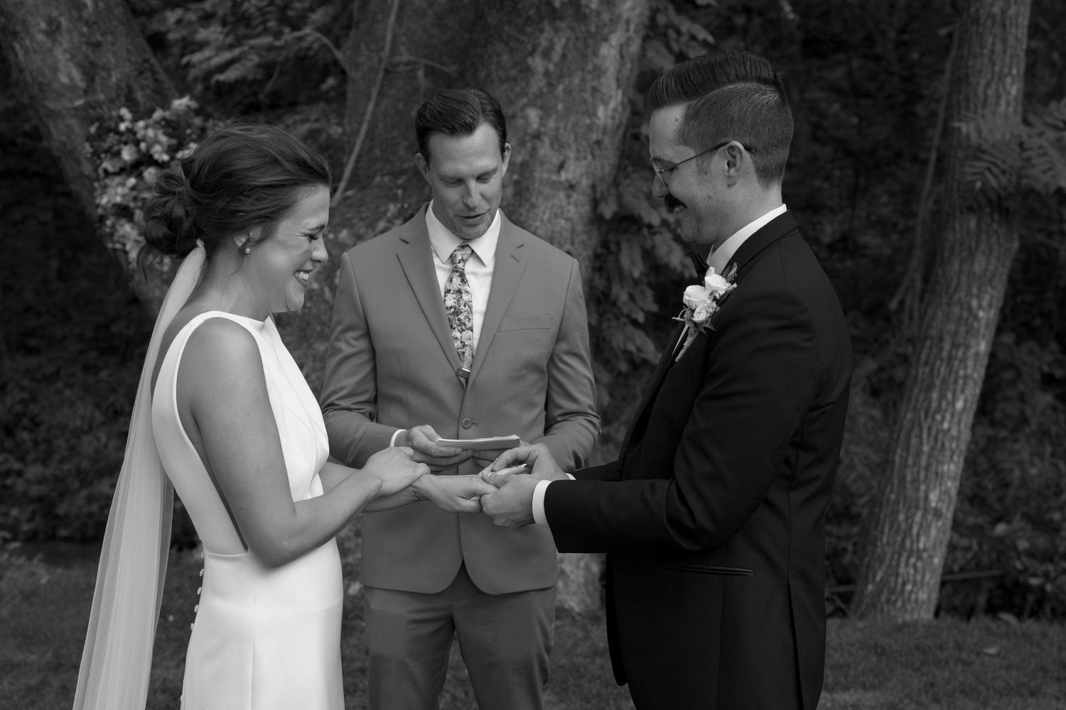 Black and white sequence of a wedding ring exchange during an intimate forest ceremony.