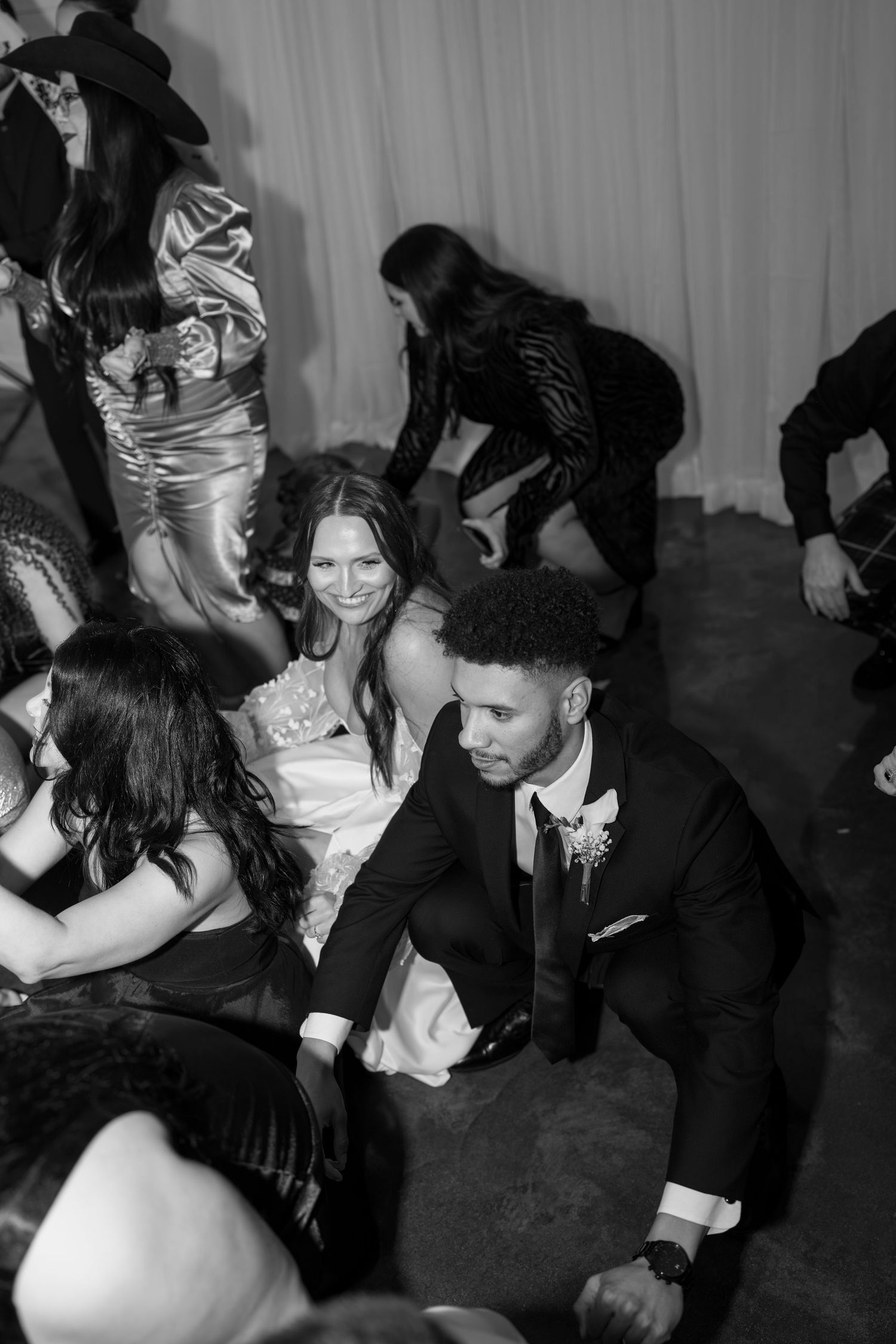 Black and white photo of wedding guests dancing and celebrating on crowded dance floor.