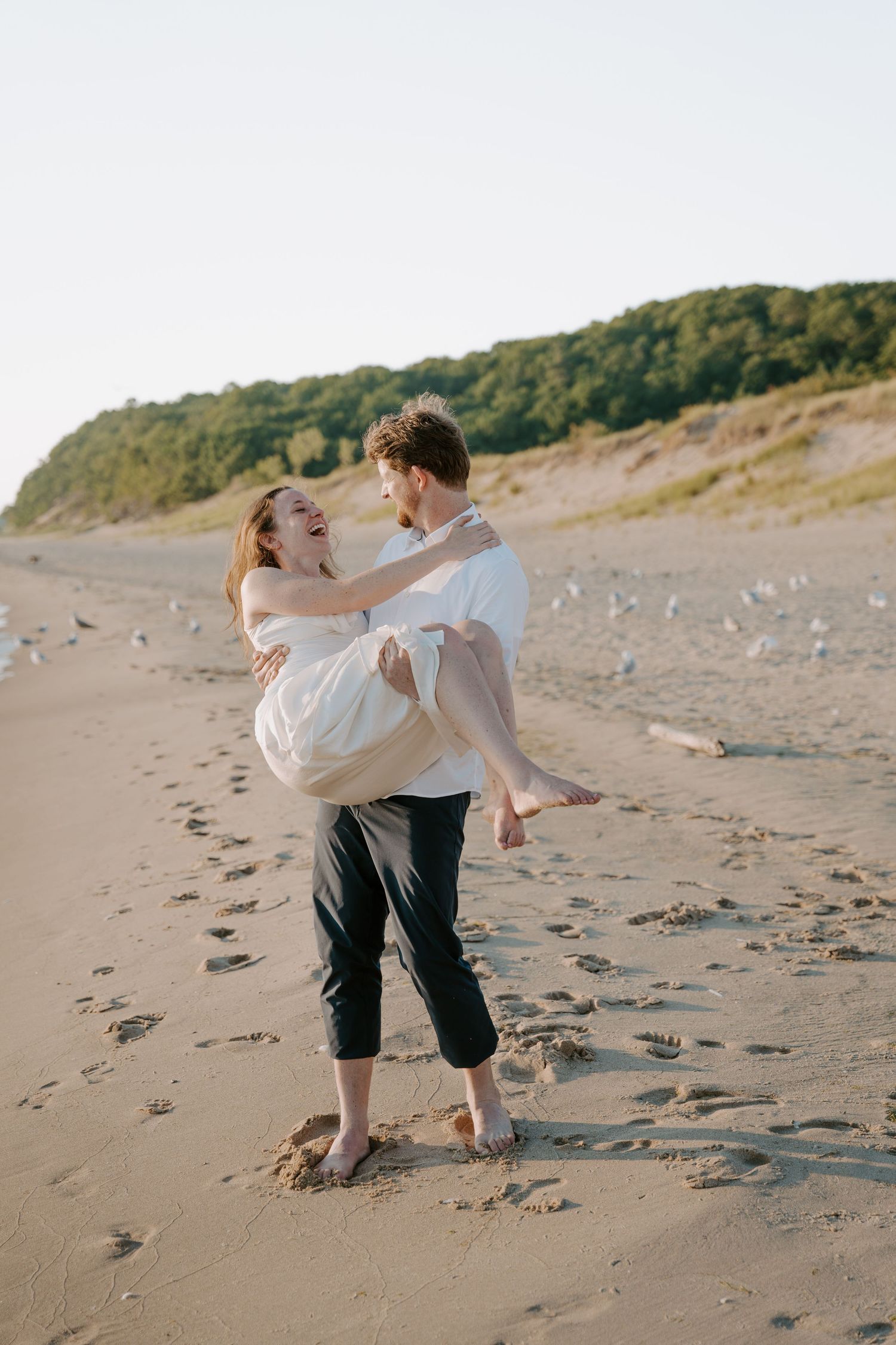 Romantic beach portrait with couple against scenic coastal cliffs.
