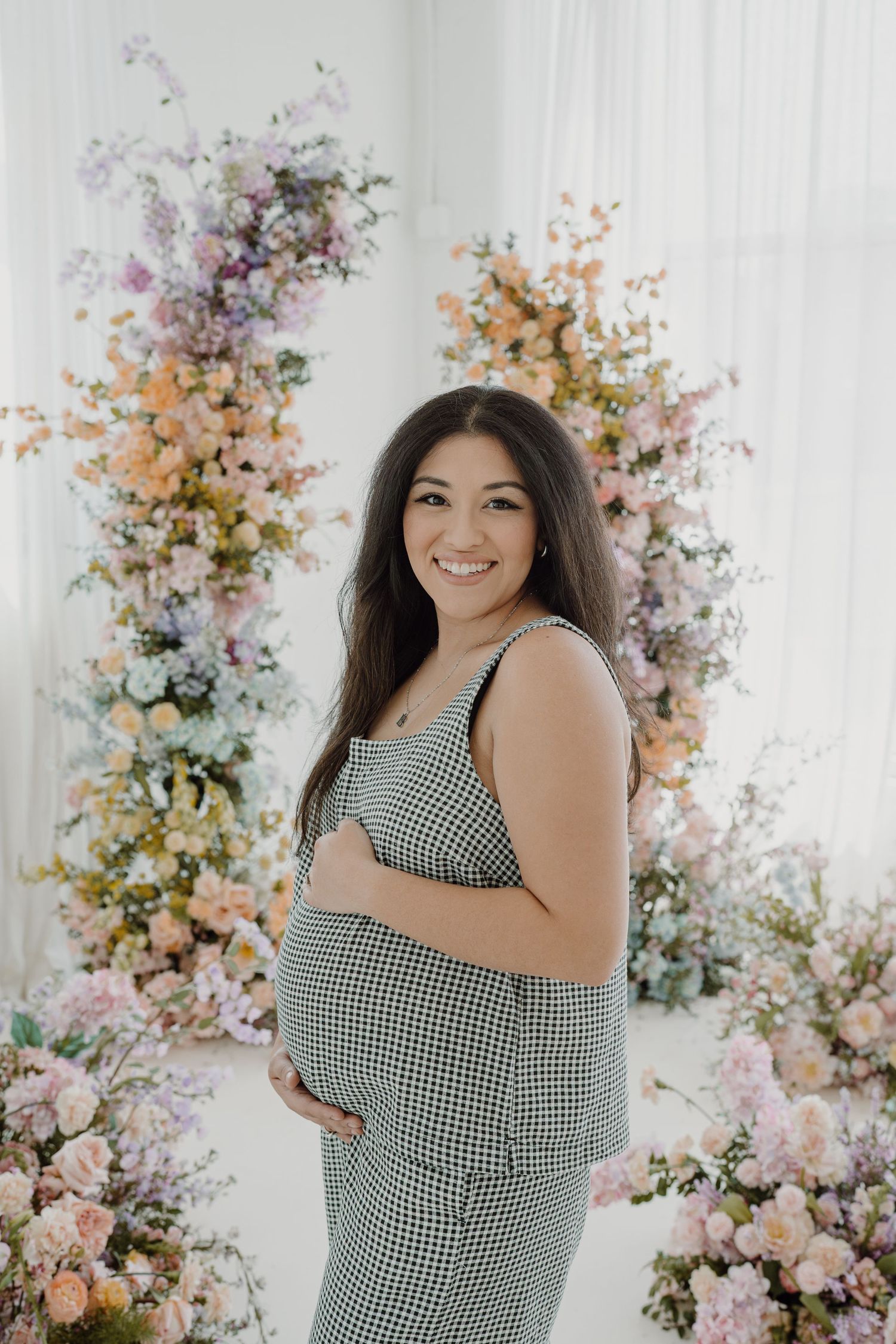 Maternity session in a light-filled studio with colorful spring flower arrangements.