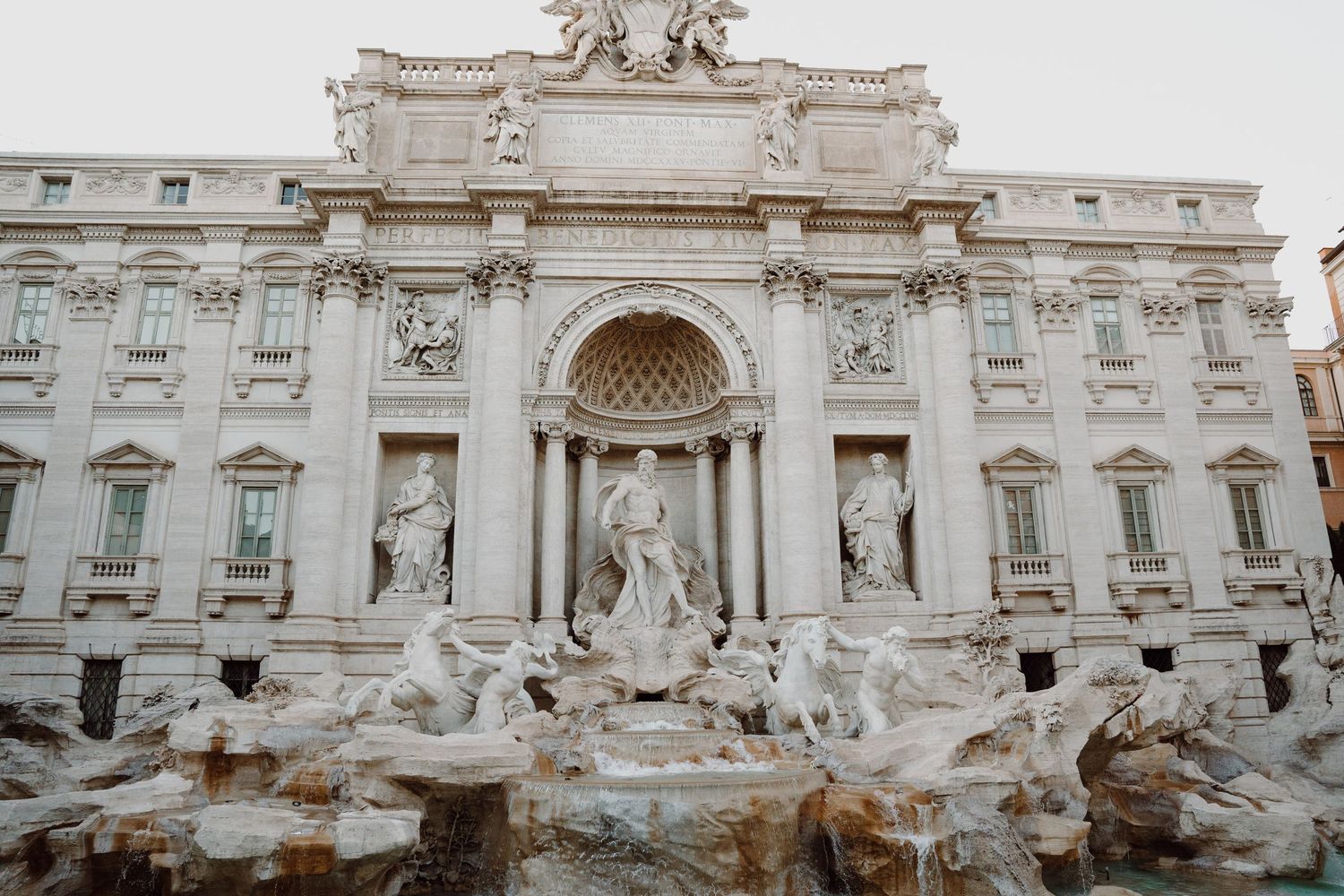 Ornate baroque architecture of the Trevi Fountain in Rome with classical statues and carved details.