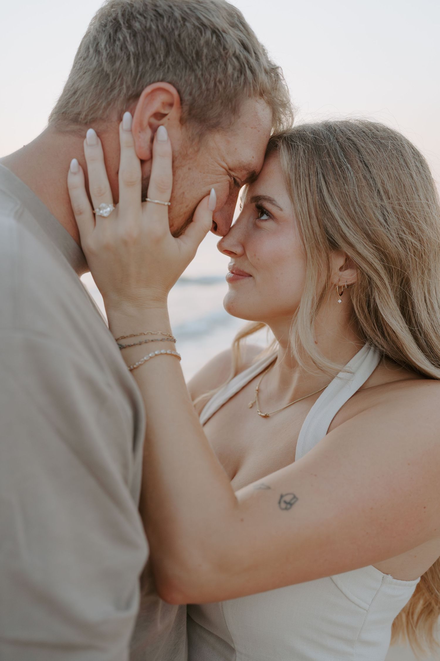 Romantic couple sharing tender moments during a beach photoshoot.