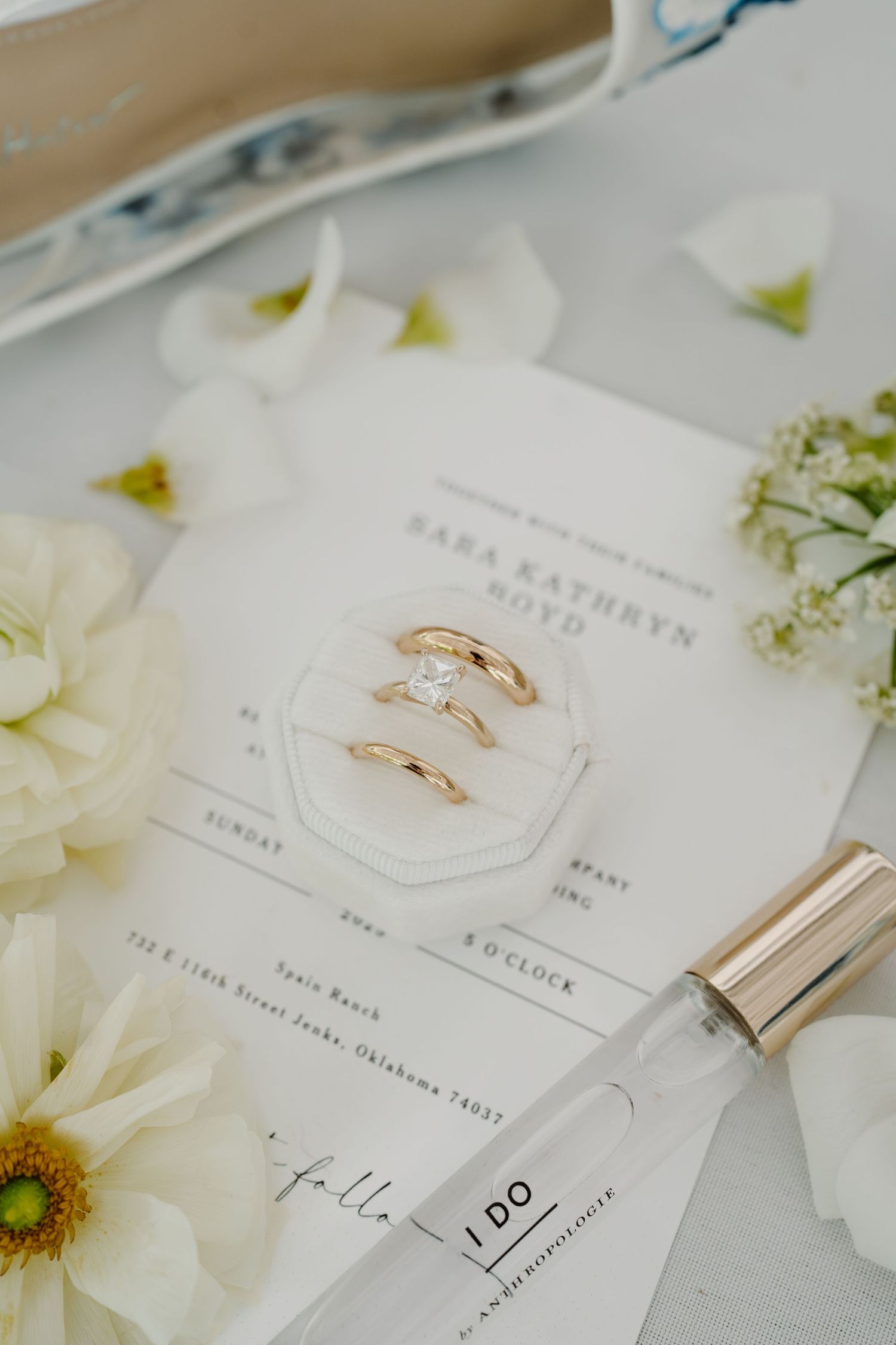 Wedding invitation suite with gold rings and white floral decorations.