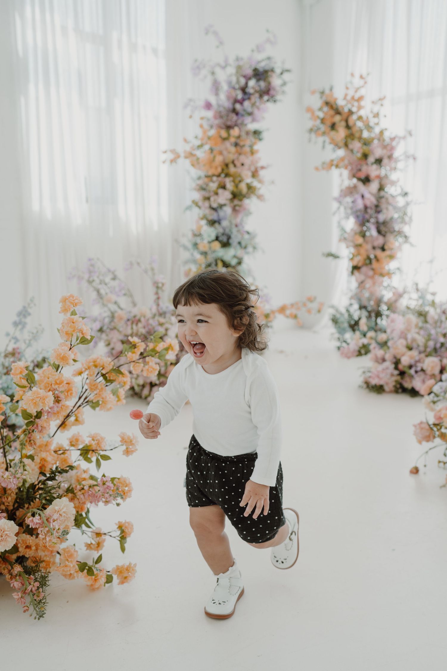Spontaneous movement captured in a bright studio space with romantic floral installations.