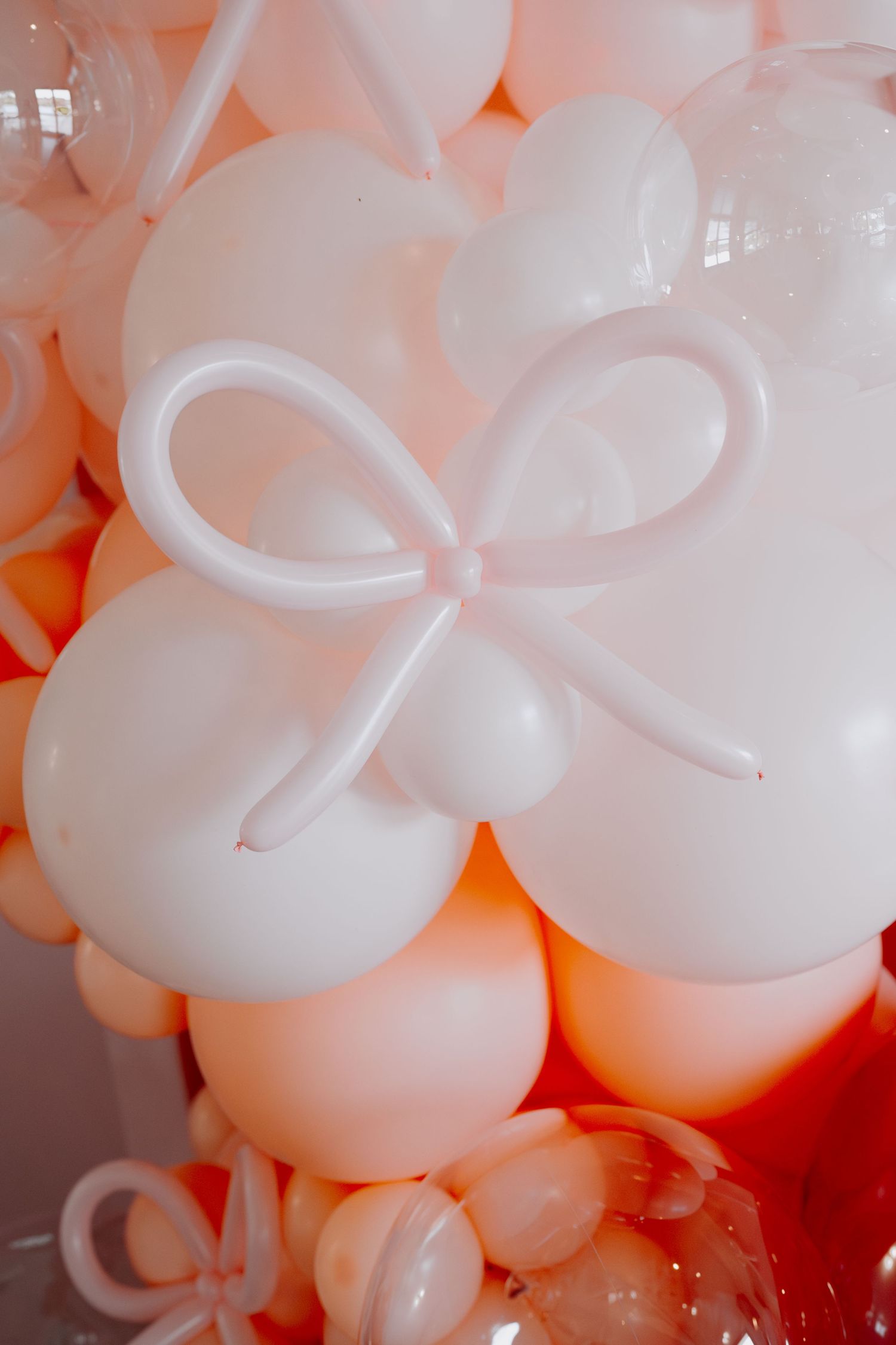 Artistic close-up of white balloon arrangements with soft pink lighting.