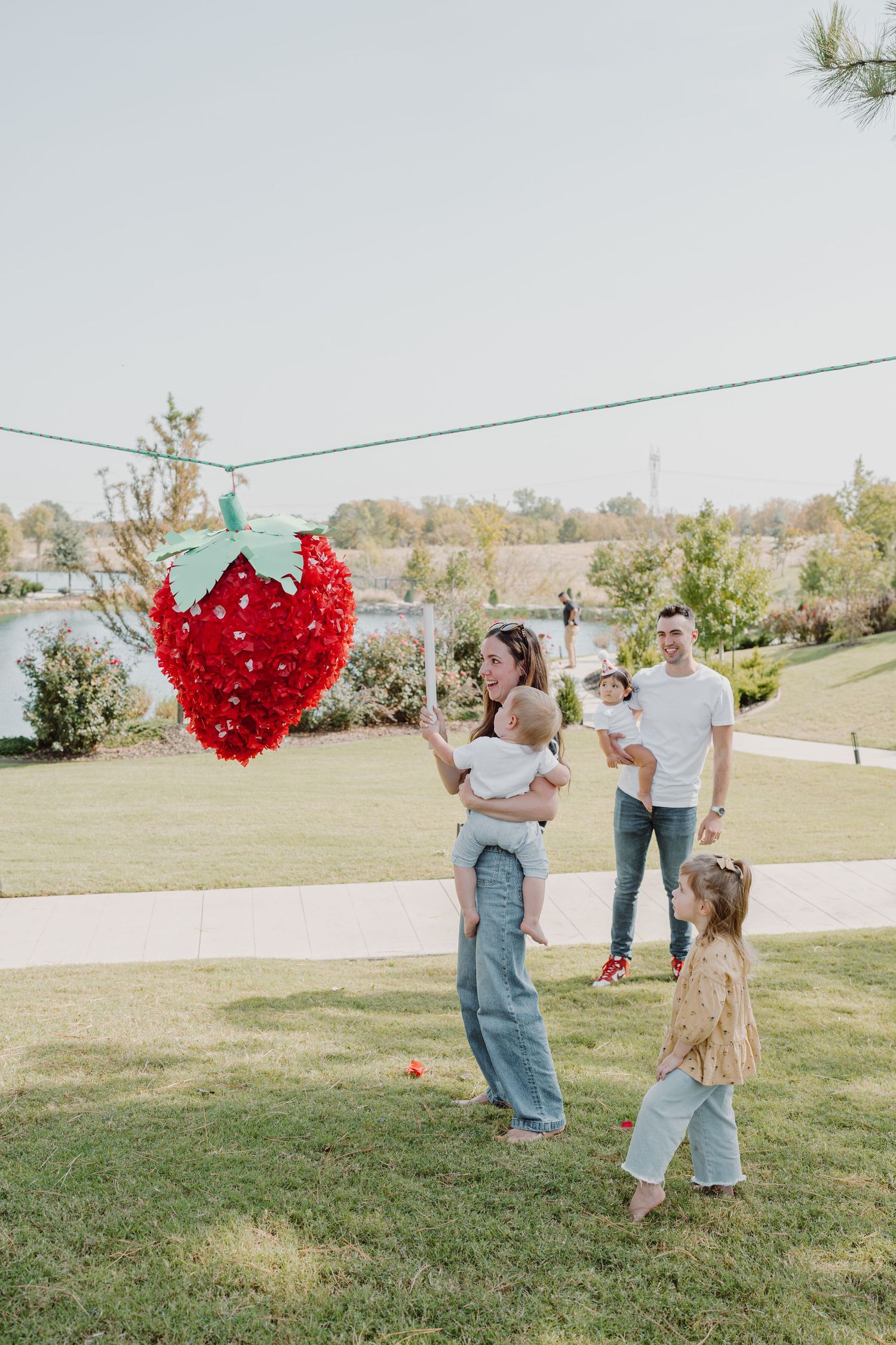 A grassy outdoor setting with people and a large red heart balloon display in the distance.