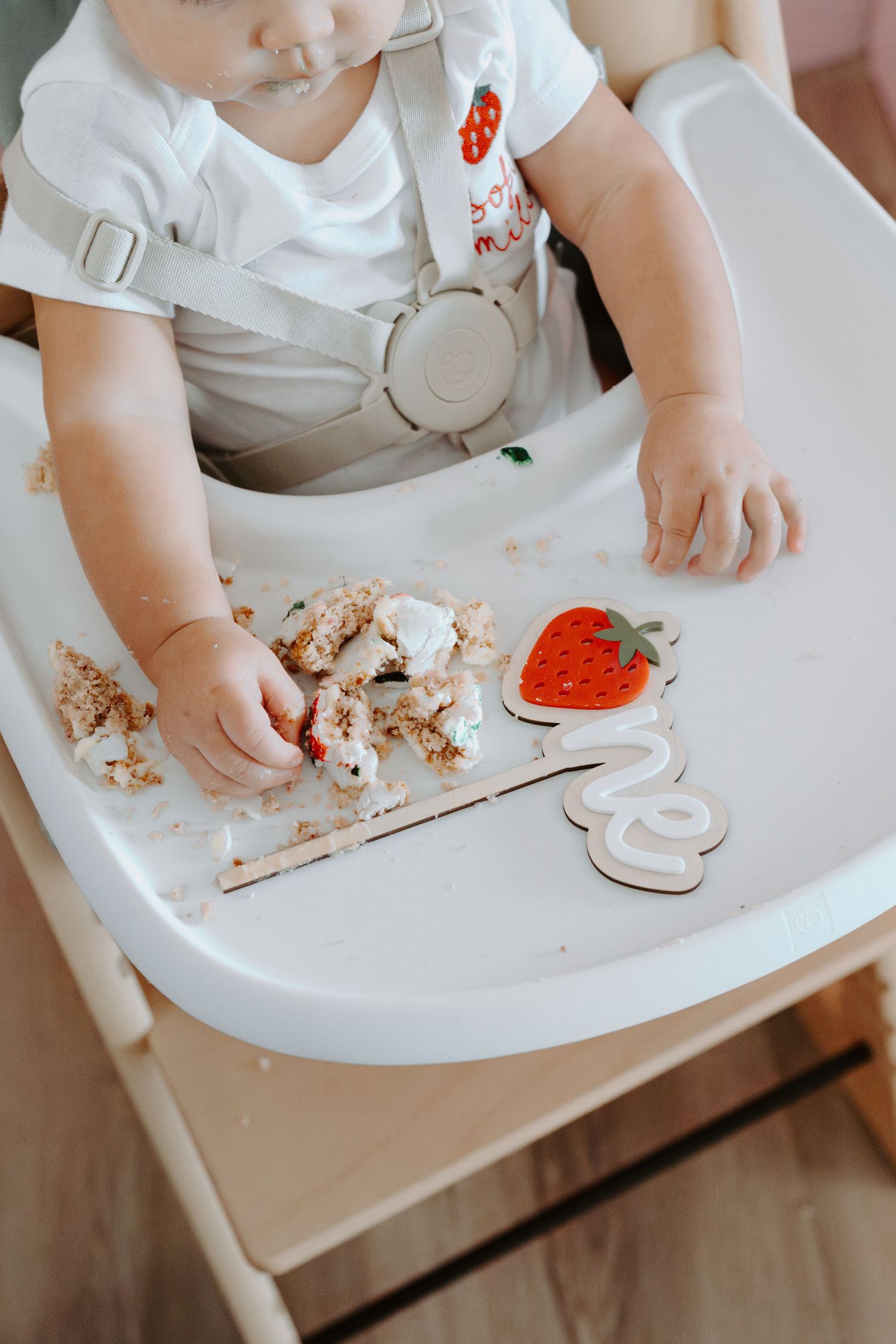 Close-up of cake and treats on a white high chair tray.
