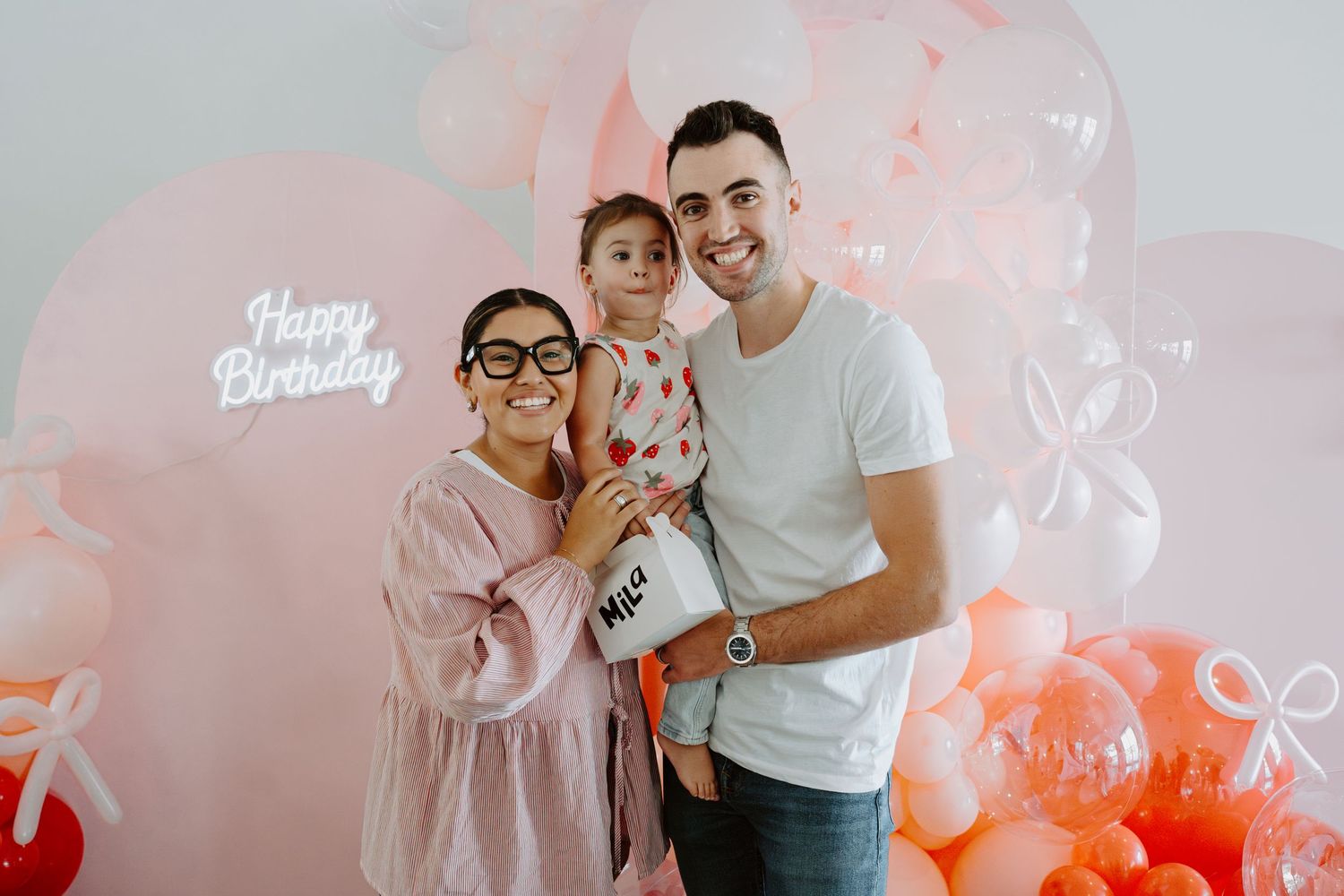 Festive balloon arrangement in pink and orange tones with 'Happy Birthday' text.
