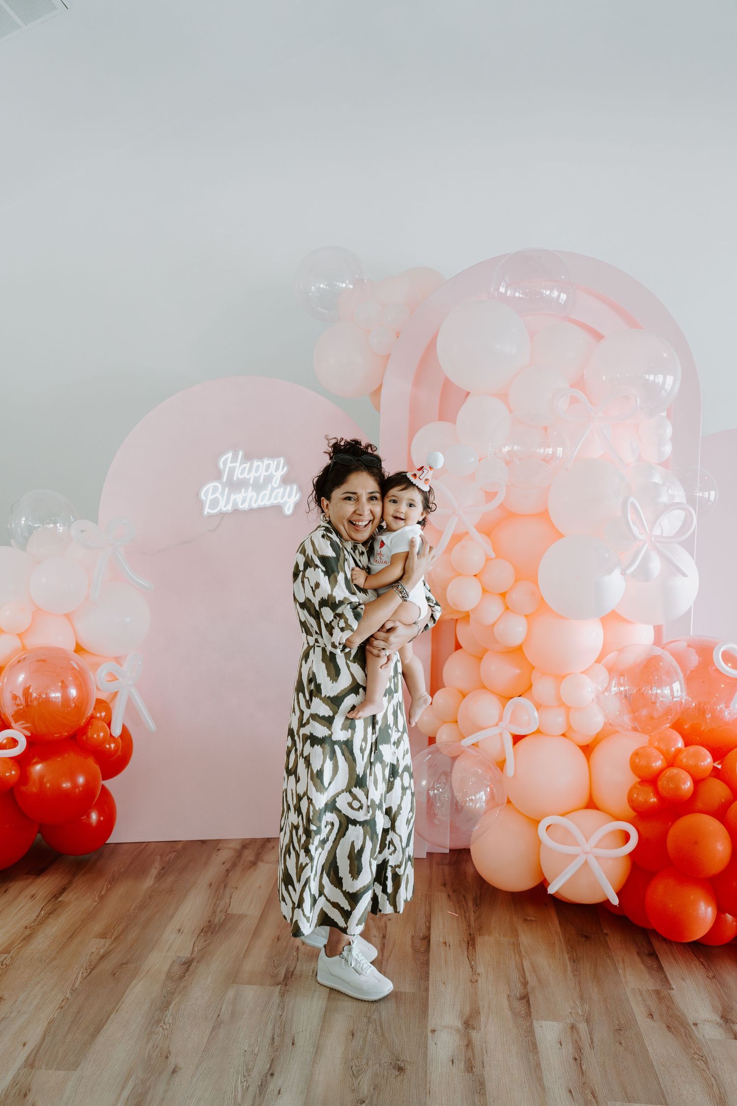 Celebratory moment captured against a backdrop of gradient balloon decorations.