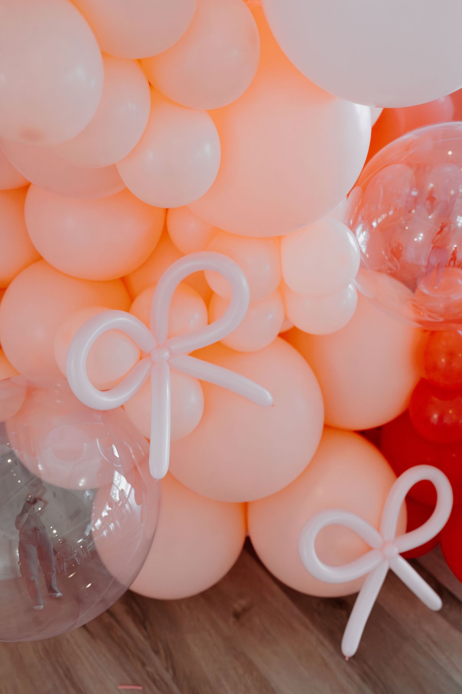 Close-up of pink and red balloon arrangement with white bow decorations.
