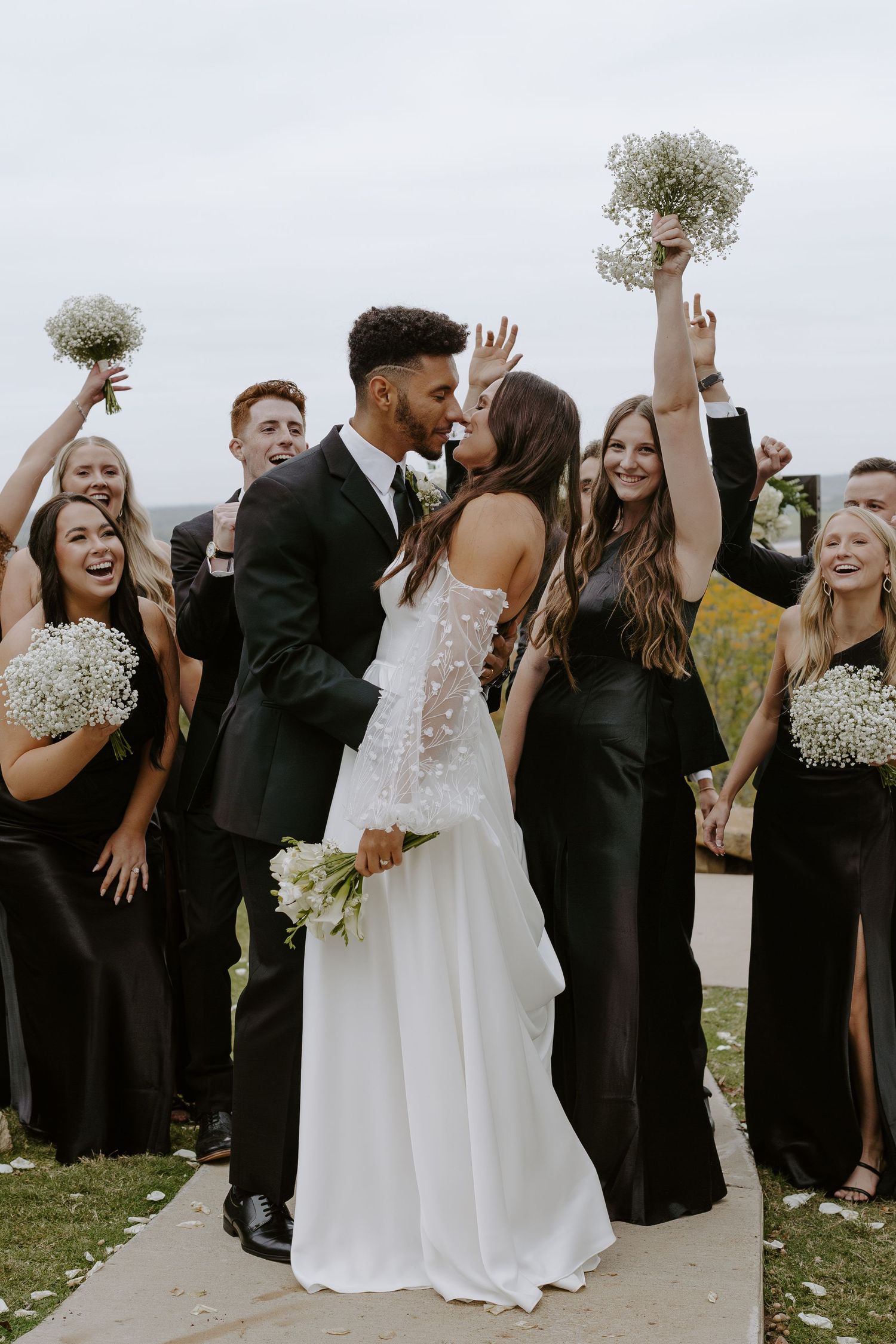 Wedding group shares a candid moment of laughter and celebration outdoors.