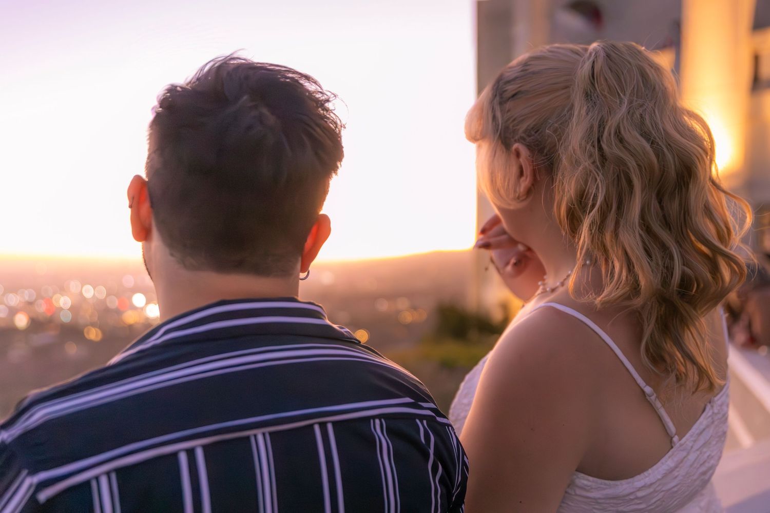 Silhouettes of a couple embrace during golden hour with warm lighting and bokeh effects in the background.