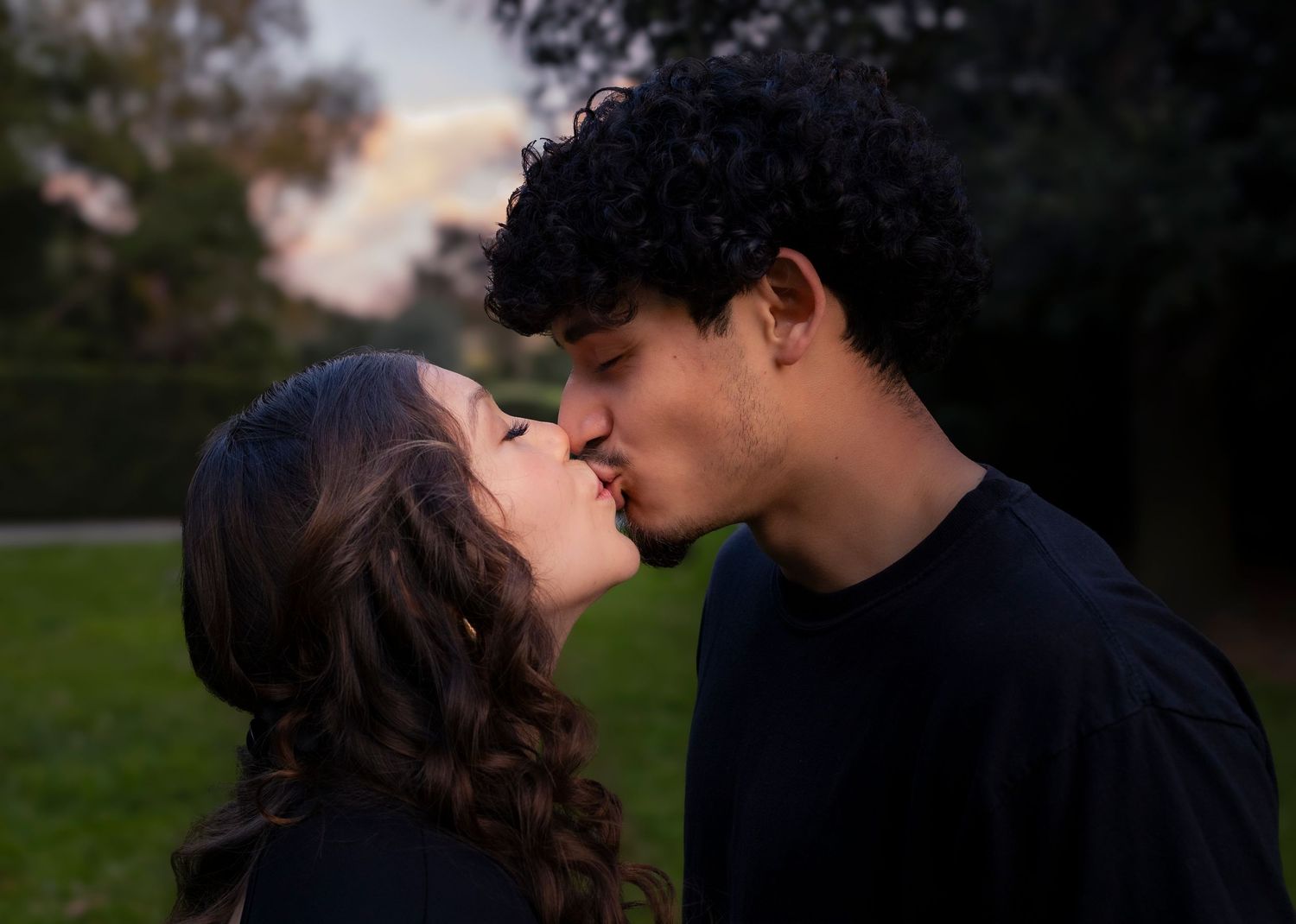 Silhouetted romantic couple portraits at dusk in park setting.