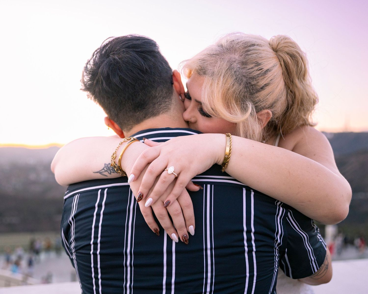 Romantic couple shares intimate moment at dusk overlooking cityscape.
