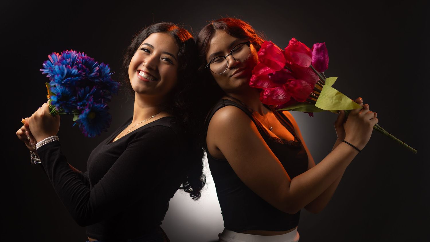 Silhouetted figures in dark background hold colorful paper fans in dramatic dance poses.