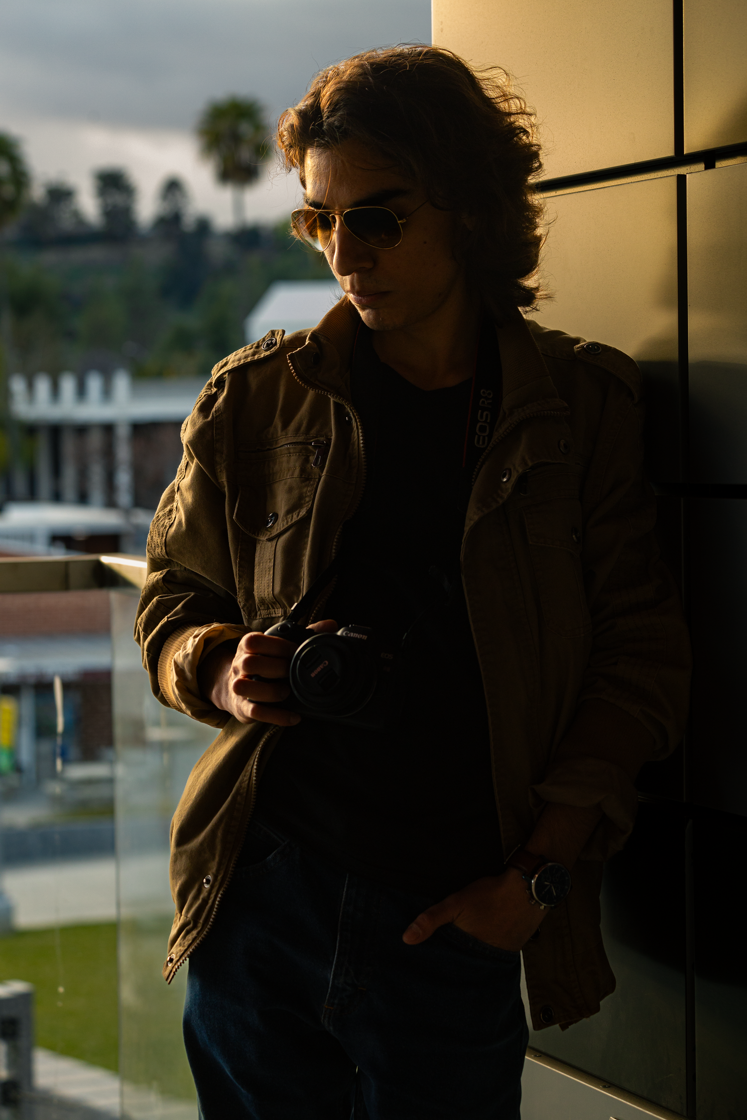 Silhouetted figure against warm-toned window light in moody urban setting.
