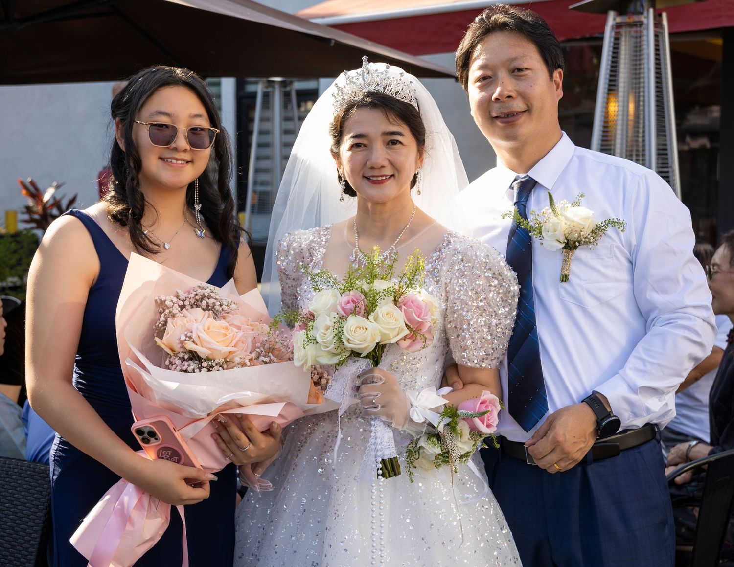 Wedding celebration outdoors with formal attire and pink floral bouquets.
