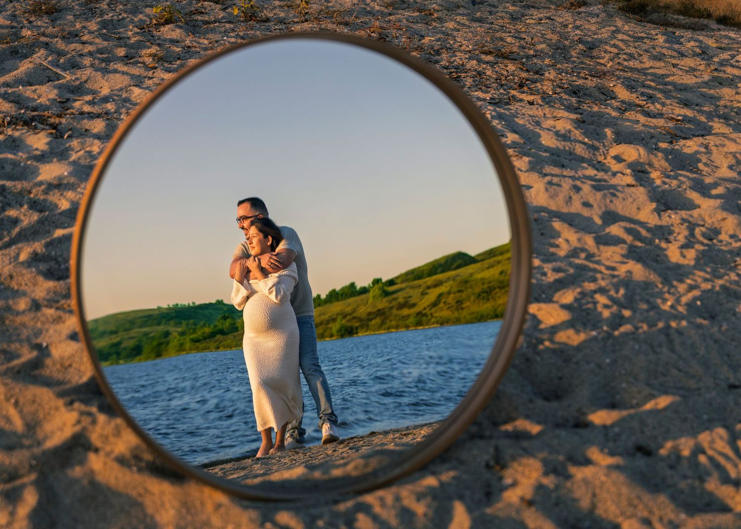 A series of circular mirror reflections on a sandy beach showing silhouettes against water and sunset sky.
