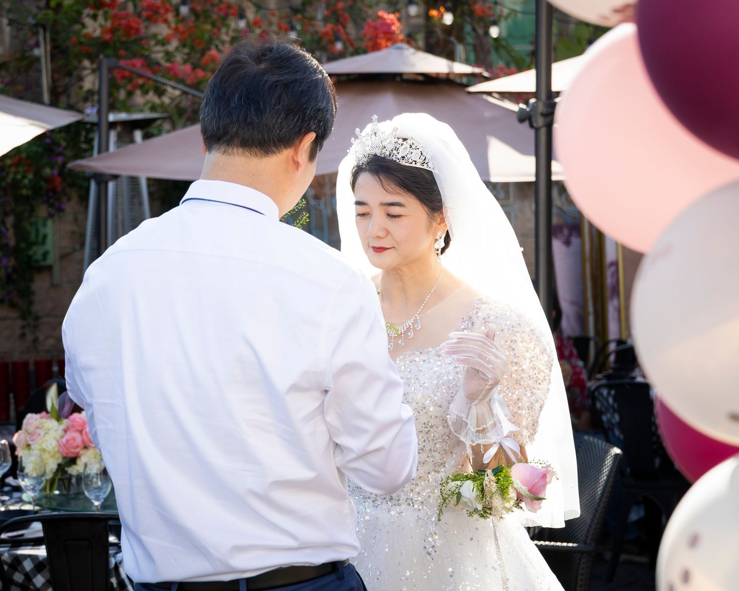 Outdoor wedding celebration with pink balloons and decorations.