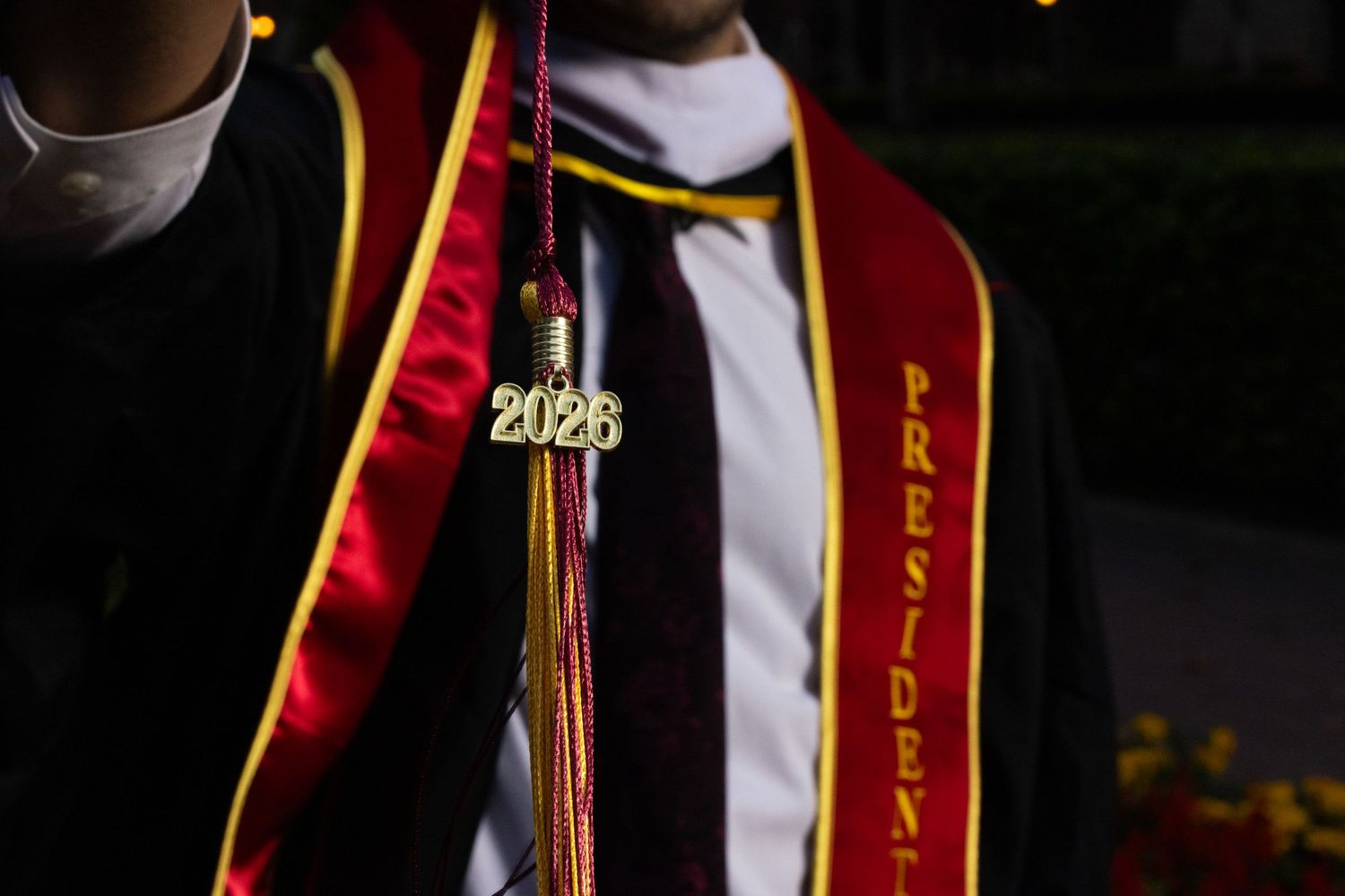 Close-up of a 2026 graduation tassel and red presidential stole on a graduate in cap and gown.