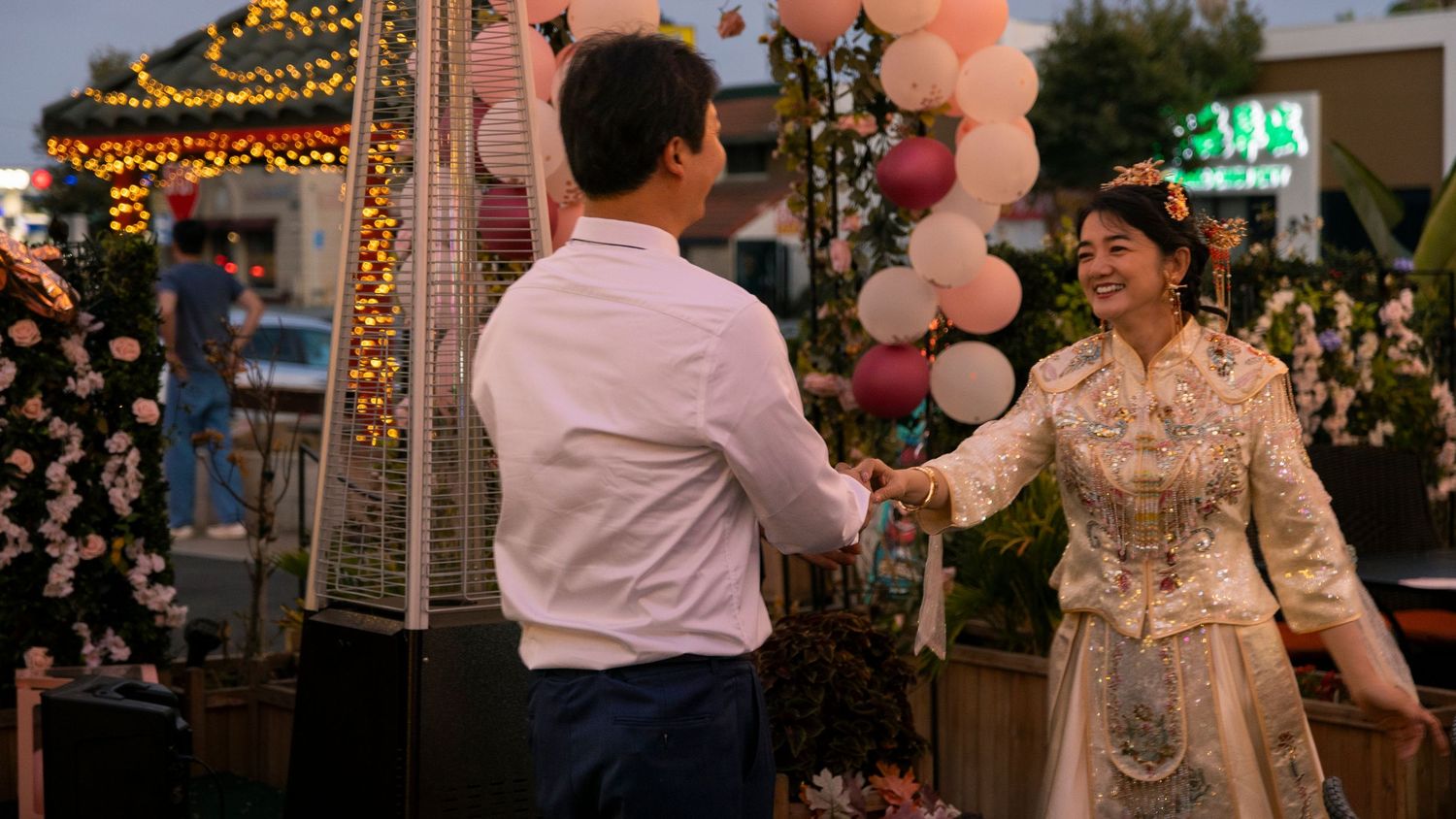 Evening celebration outdoors with pink balloons and string light decorations.