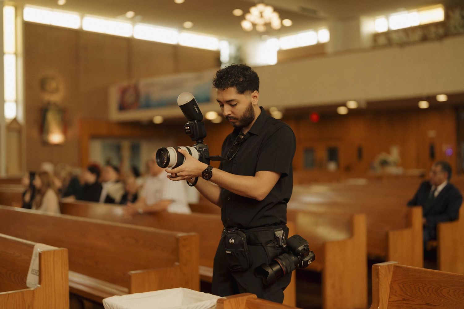 Professional photographer with camera captures candid moments during a wedding ceremony in a church sanctuary.