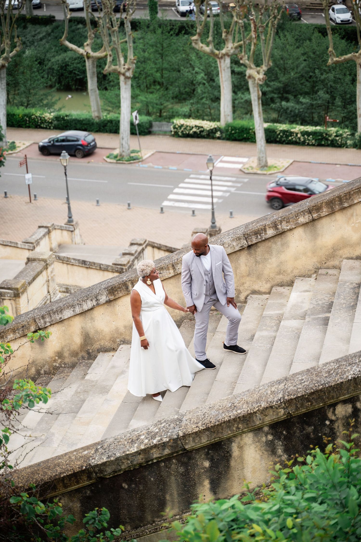 Aerial view of Black couple holding hands descending grand stone staircase in European city.