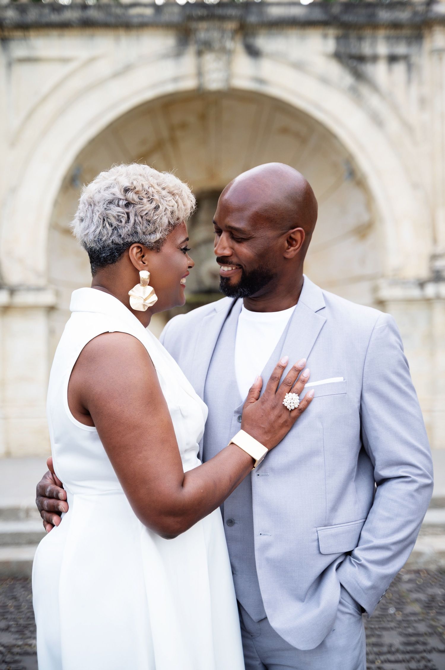 Couple gazing at each other lovingly in front of a historic stone arch backdrop.