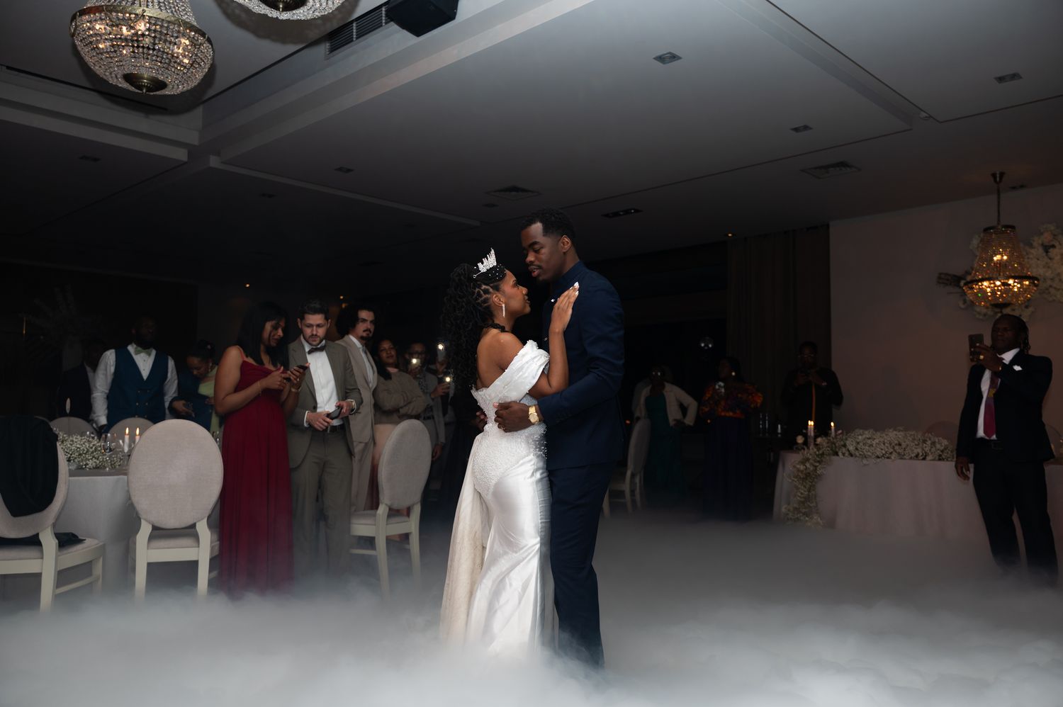 Bride and groom share first dance surrounded by low-lying fog at elegant wedding reception venue.