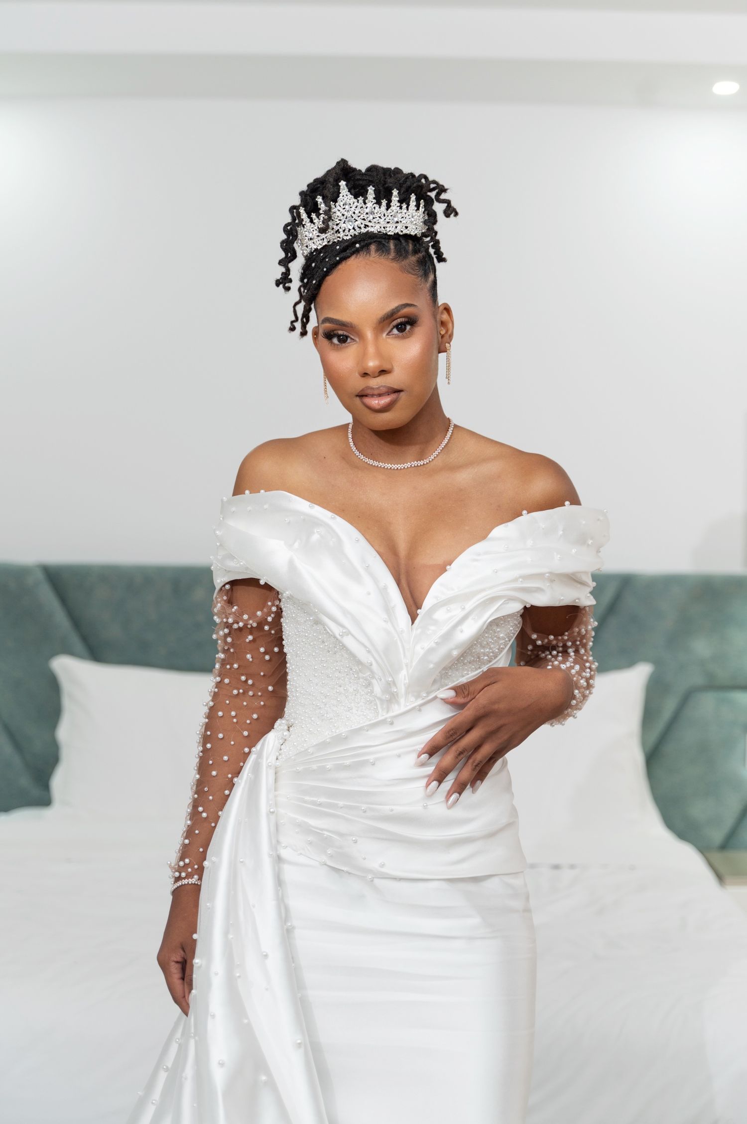 Stunning Black bride in off-shoulder pearl wedding dress and crystal crown poses.