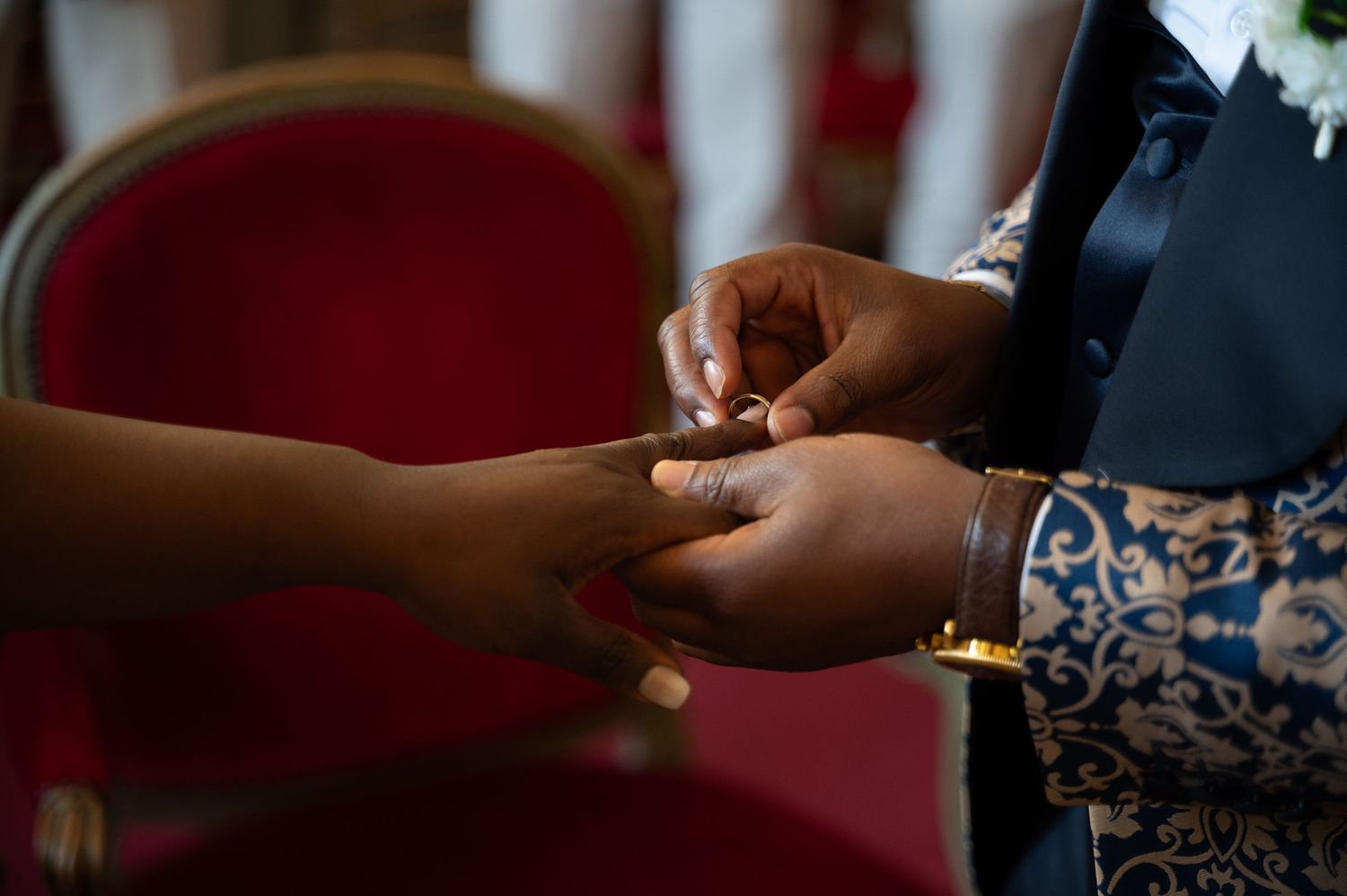 Close-up of groom placing wedding ring on bride's finger during a wedding ceremony.